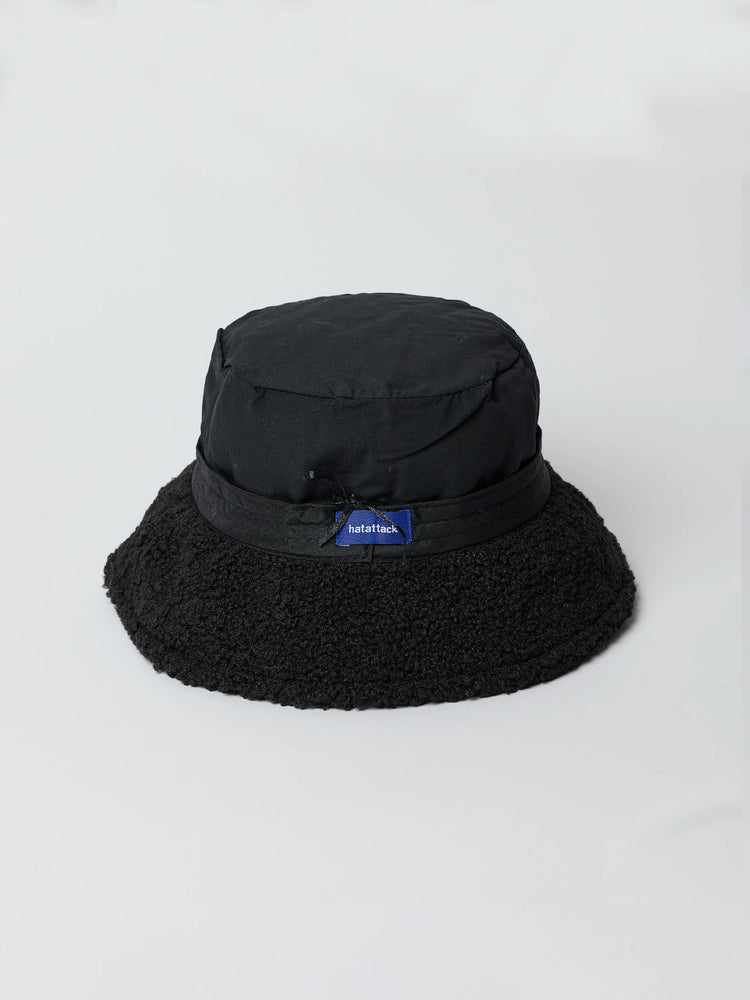 Black quilted bucket hat with a black fuzzy brim. Small navy blue logo tag.