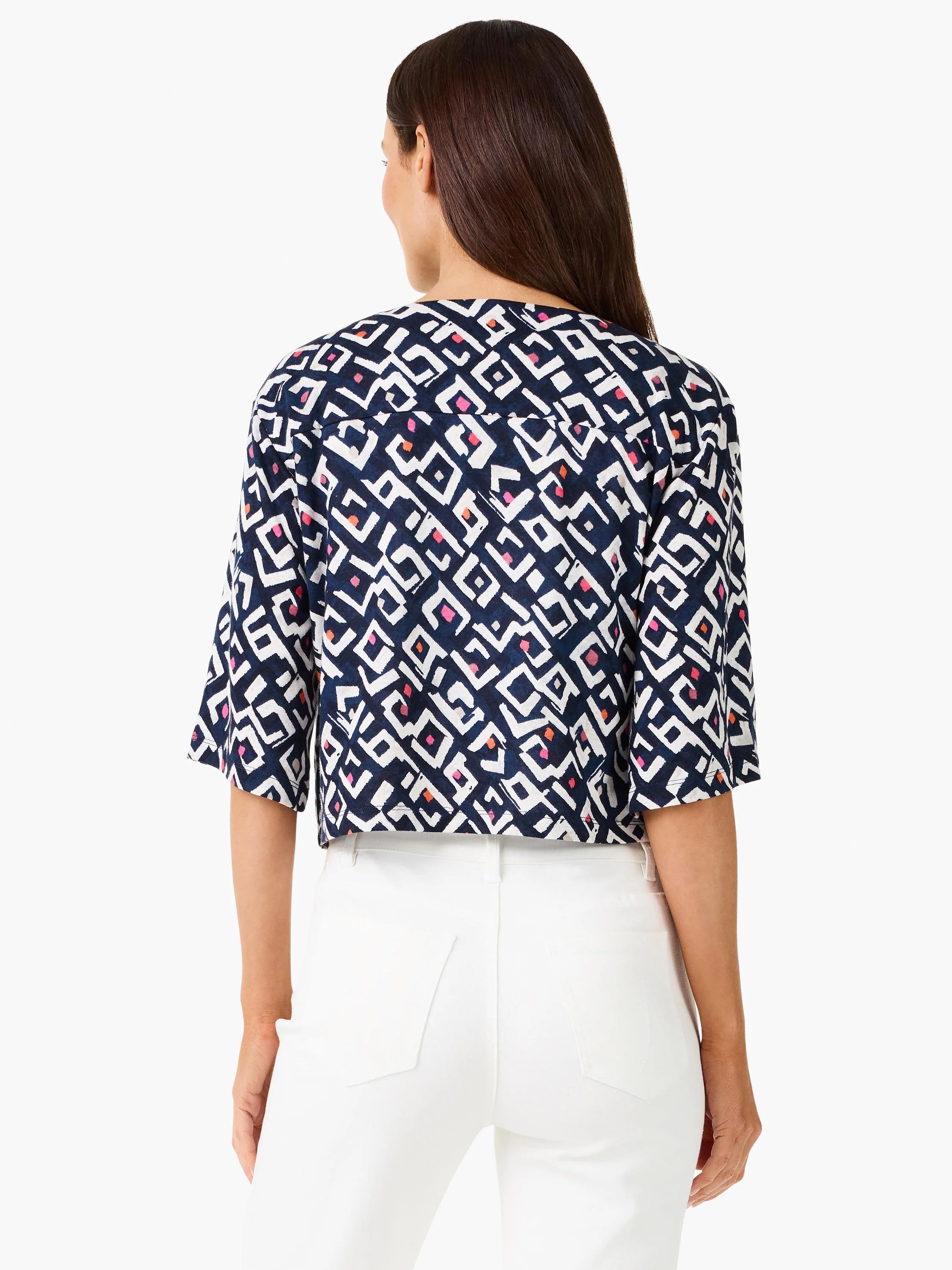 Dark indigo cardigan with white geometric angles, accented by pink and orange shapes. Model from back.