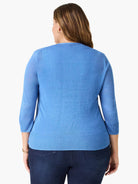 Sky blue knit cardigan, back view. Model wears 3/4 sleeves with ribbed cuffs and a ribbed hem.