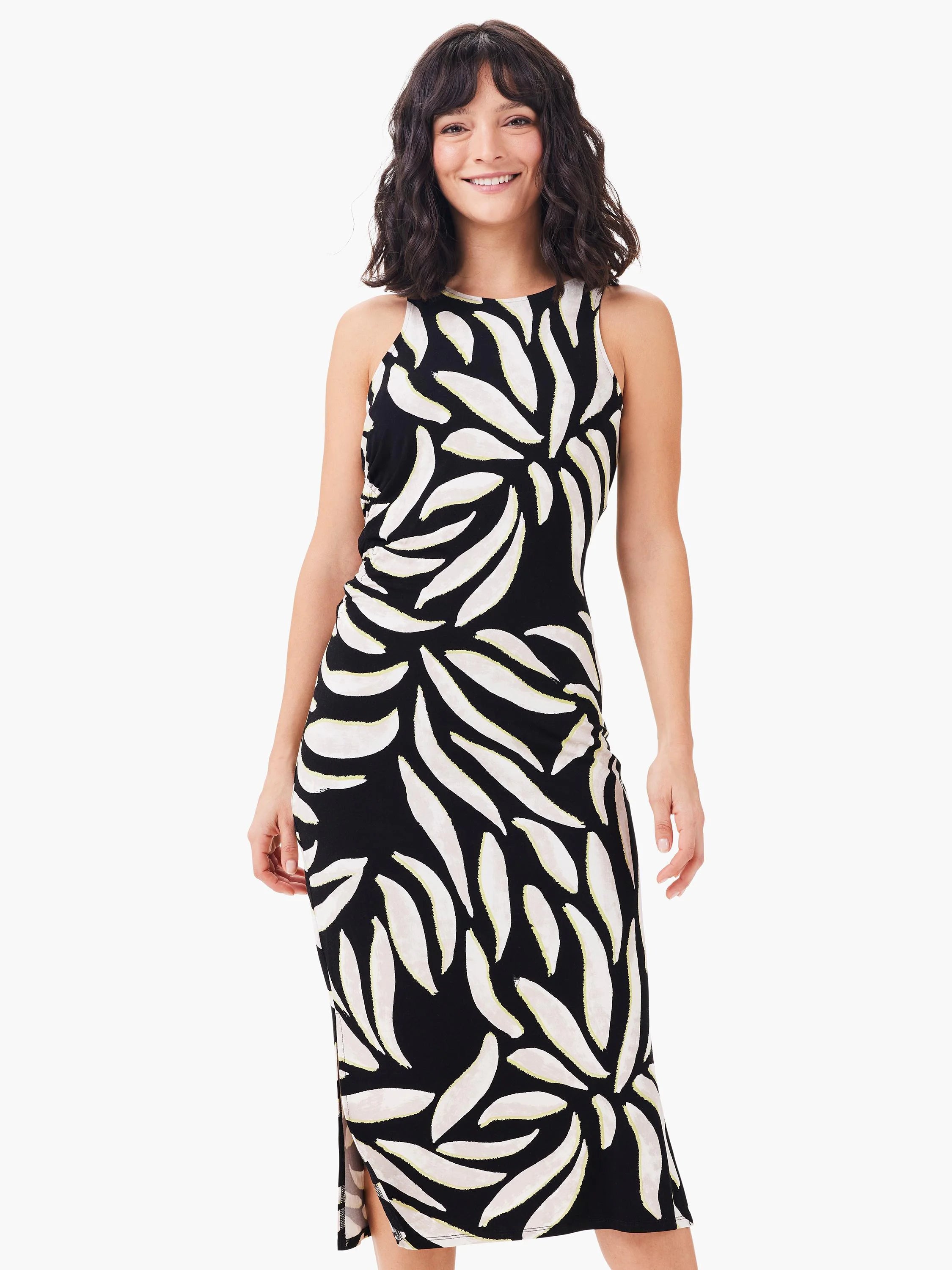 Black sleeveless midi dress with cream leaves outlined in pale yellow, worn by a smiling woman.