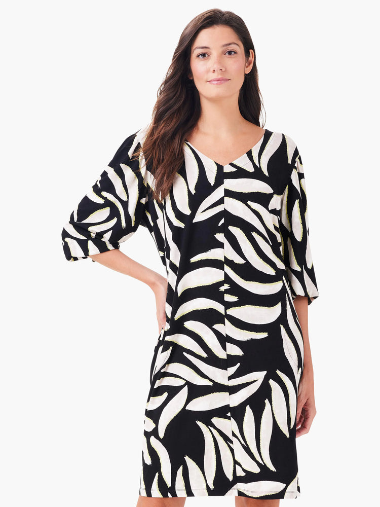 Black V-neck dress with 3/4 sleeves and a pattern of large off-white, leaf-like shapes subtly outlined in pale green.