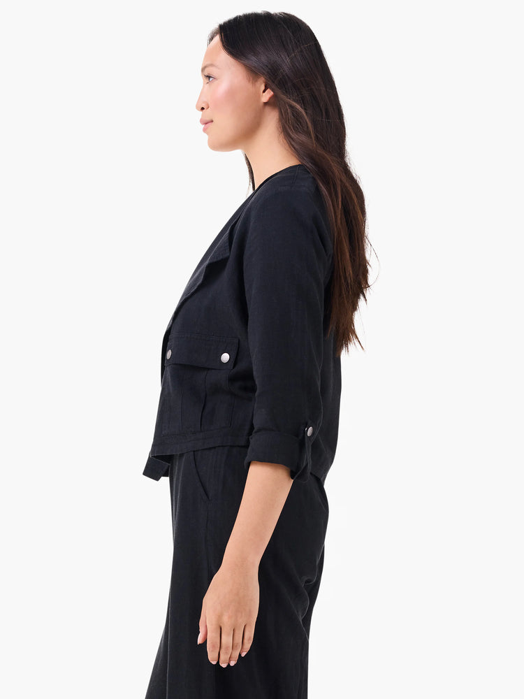 Black linen moto jacket with wide lapels, two flap chest pockets, and rolled 3/4 sleeves with silver buttons.