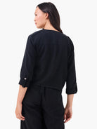 Cropped black linen moto jacket with shoulder epaulets and 3/4 sleeves rolled & secured with silver buttons.