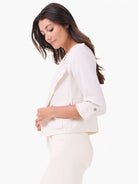 Off-white Rumba linen moto jacket with open lapels, rolled 3/4 sleeves, and snap-button flap pockets.