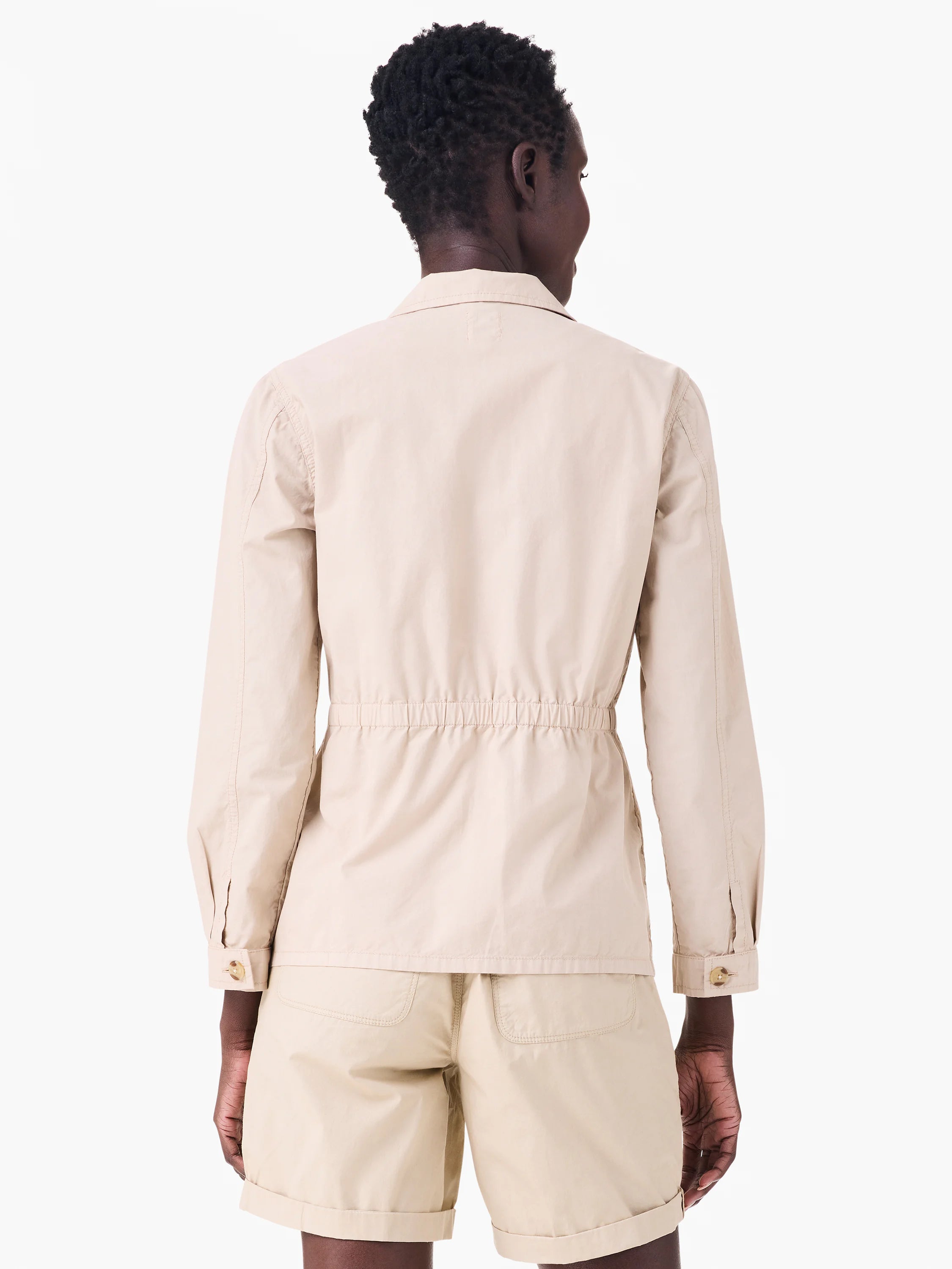 Back view of a light beige poplin jacket with long sleeves and a cinched elastic waist.