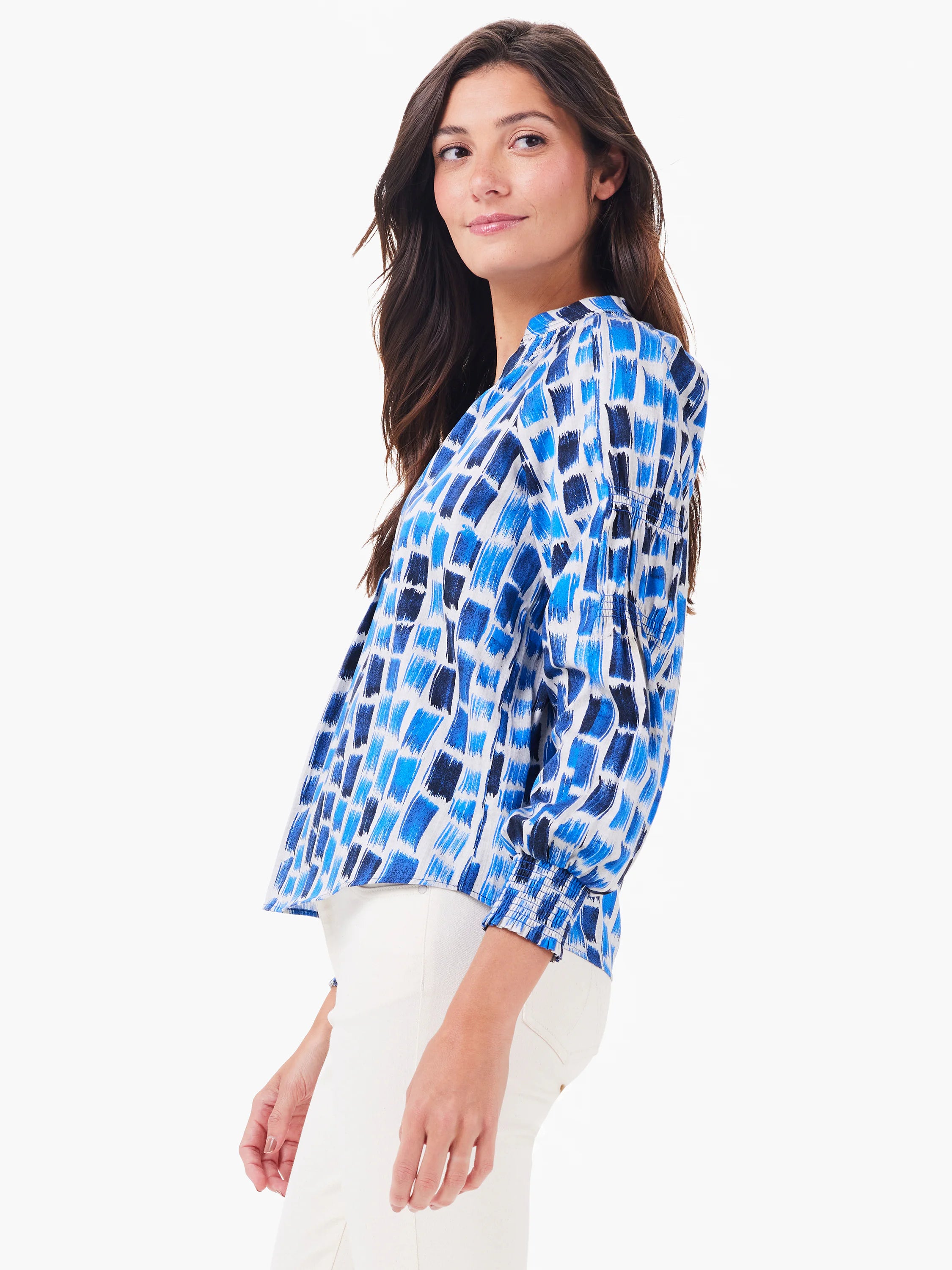 White blouse with varied blue brushstroke pattern, collared, long sleeves with smocked cuffs.