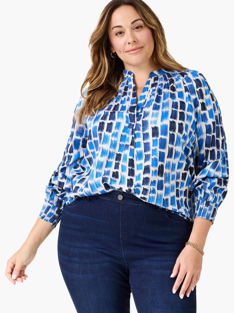 White top with varying shades of blue brushstroke pattern, V-neck, gathered shoulders, and 3/4 shirred sleeves.