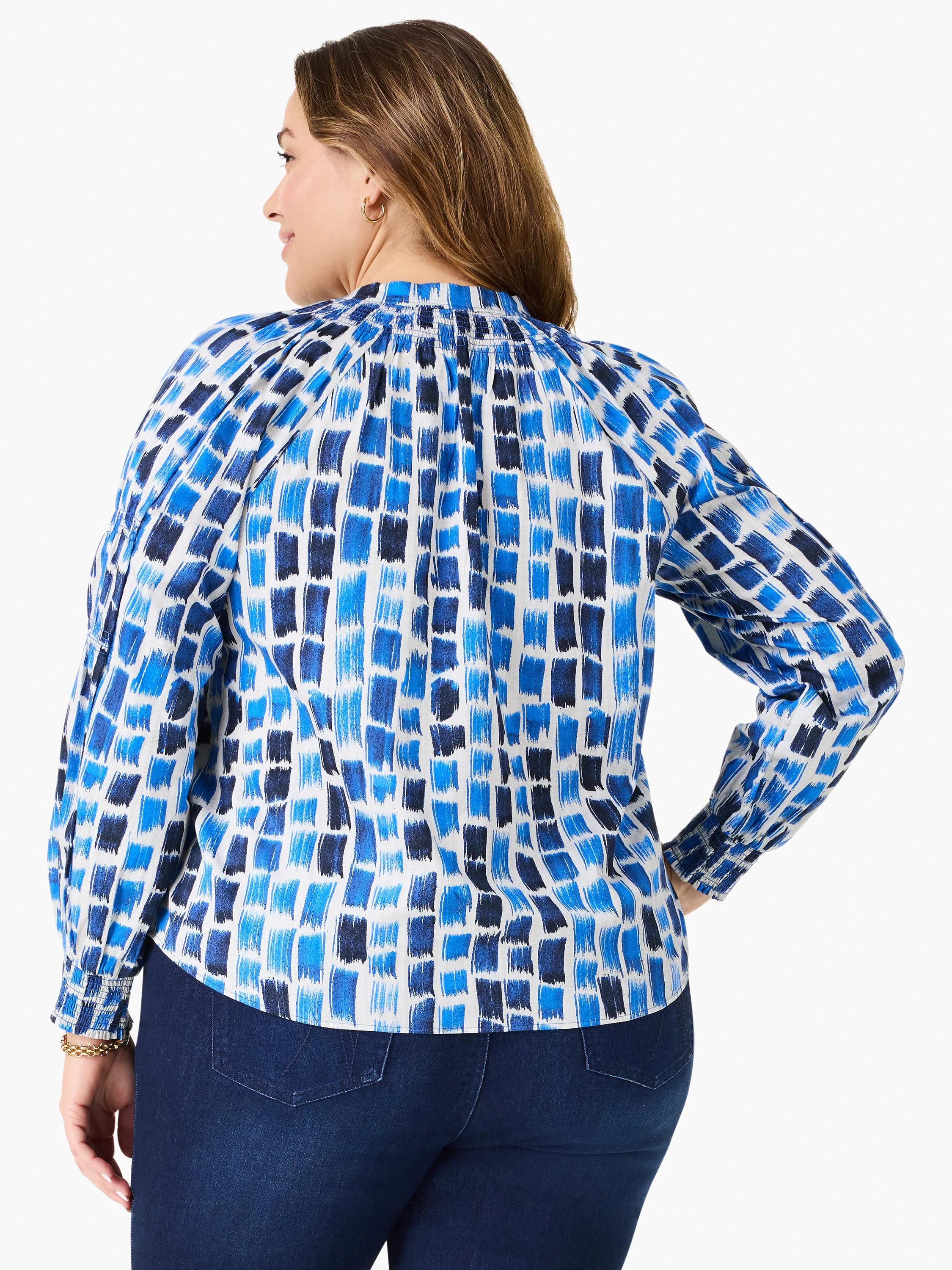 White long-sleeve top with varied blue brushstroke blocks, smocked cuffs, and gathered back neckline.