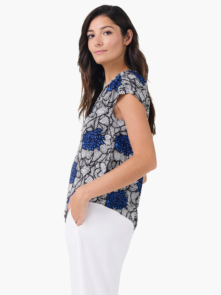 Short-sleeved top with vivid blue, white, and black abstract petal bloom pattern.