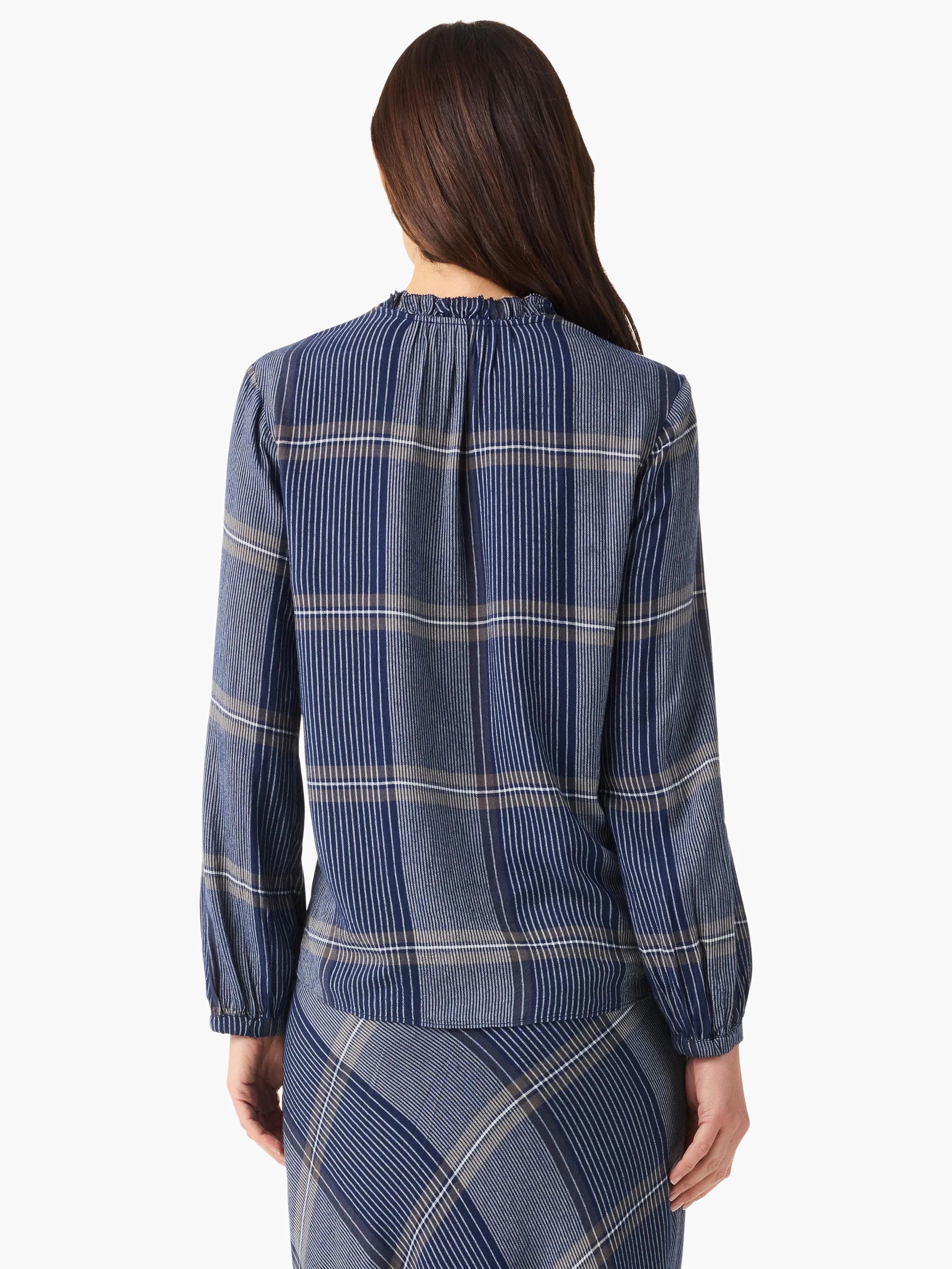 Rear view of navy blue and taupe plaid long-sleeve blouse with ruffled neckline. The blouse is shown paired with a...