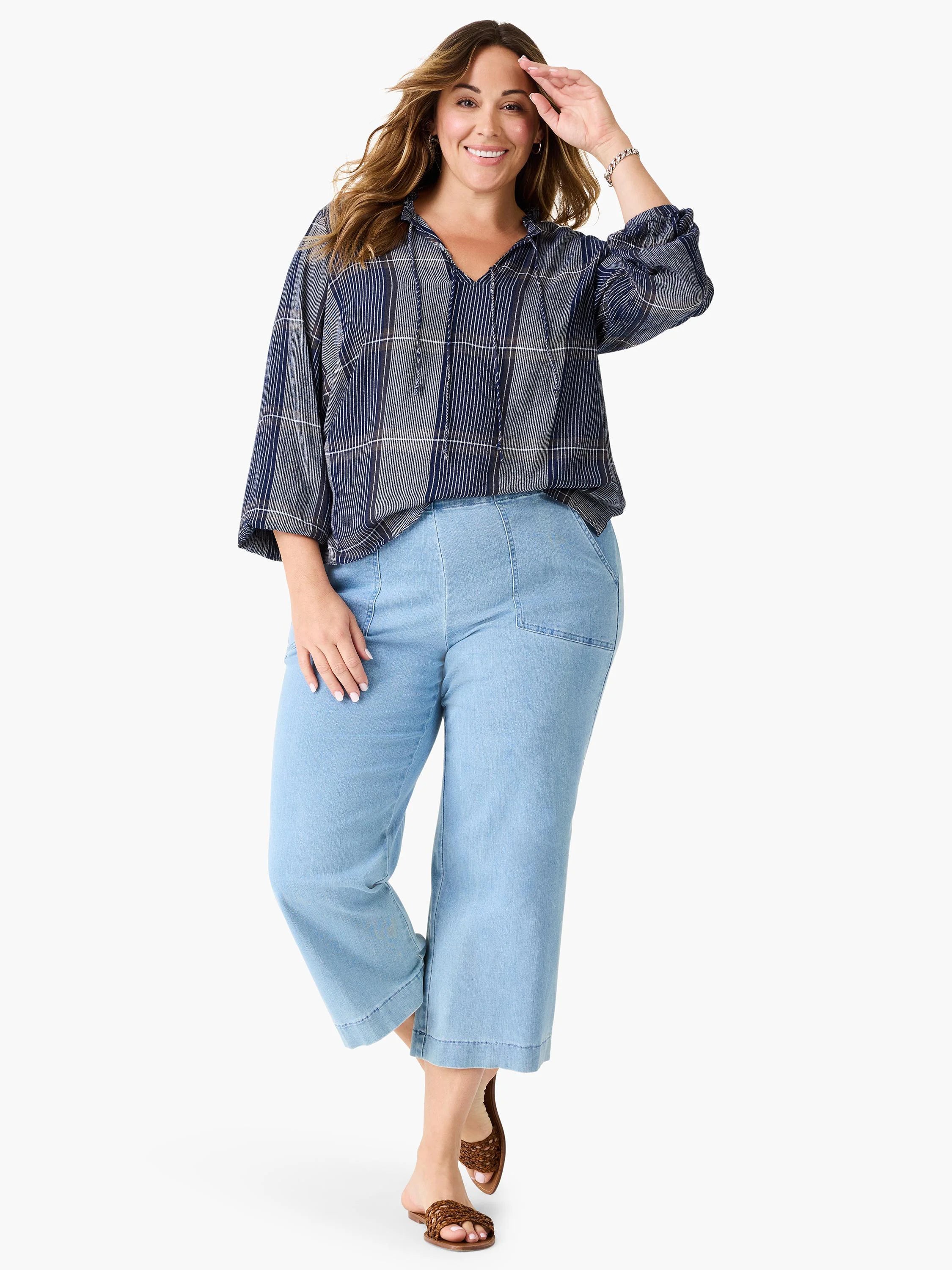 Model wears light blue cropped jeans with patch pockets and a navy and white plaid top. Brown sandals.