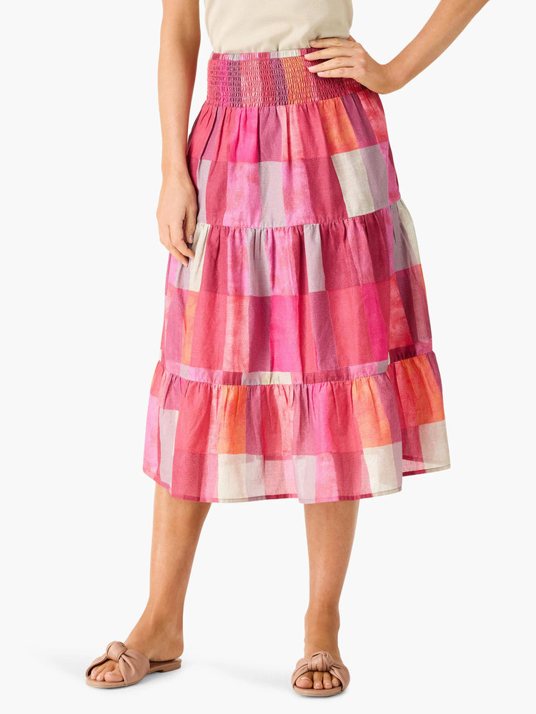 Midi-length tiered skirt in sunset hues of pink, orange, and beige; large, irregular plaid pattern.