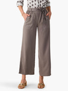 Drapey taupe wide-leg utility pants, elasticized waist with self-tie, and front patch pockets. Cropped above the ankle.