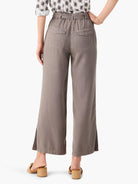 Taupe wide leg pants, cropped with side slits. Features back flap utility pockets and an elasticized waist.