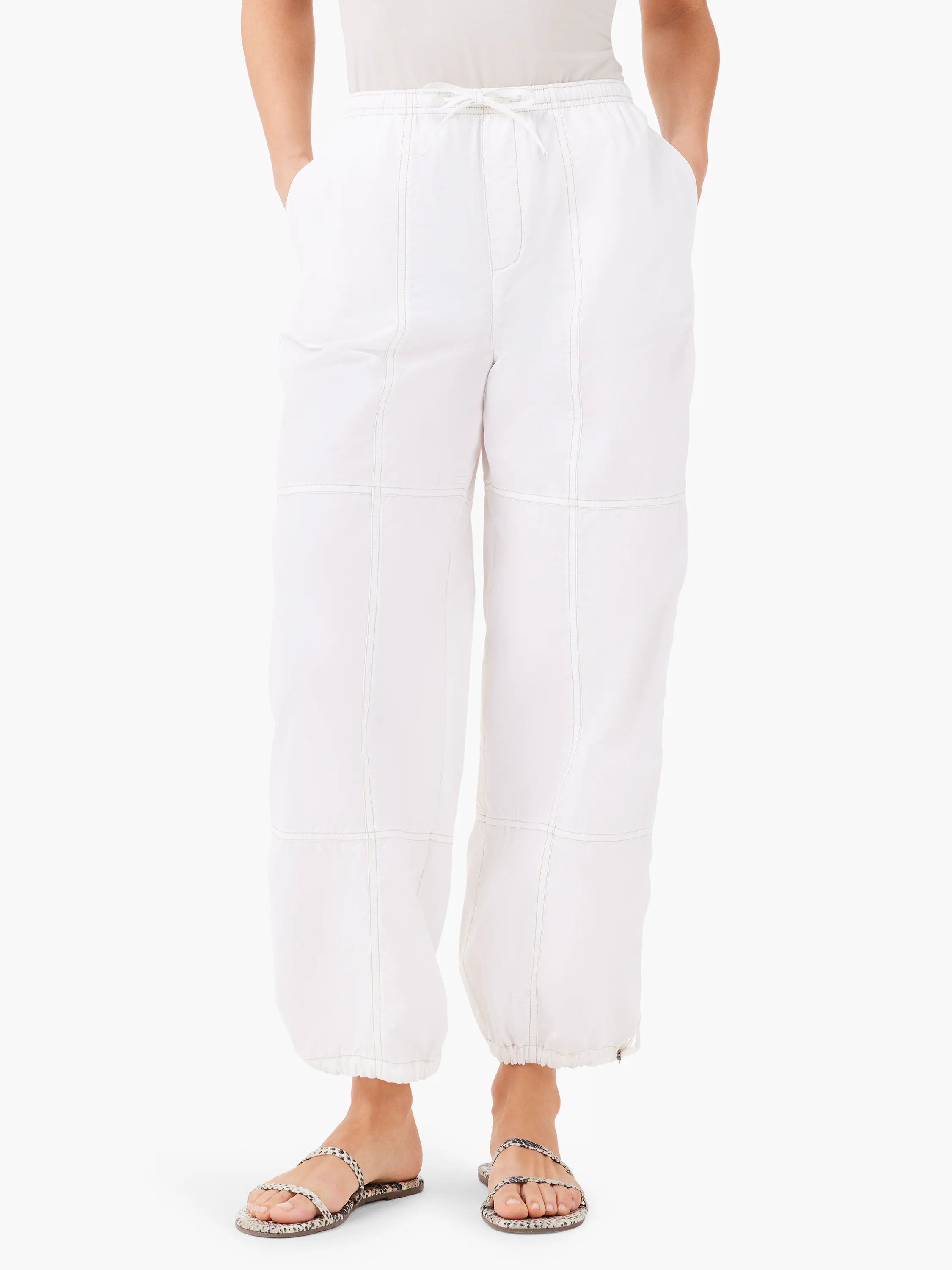 White ankle-length pants with light beige stitching, drawstring waist, and pockets.