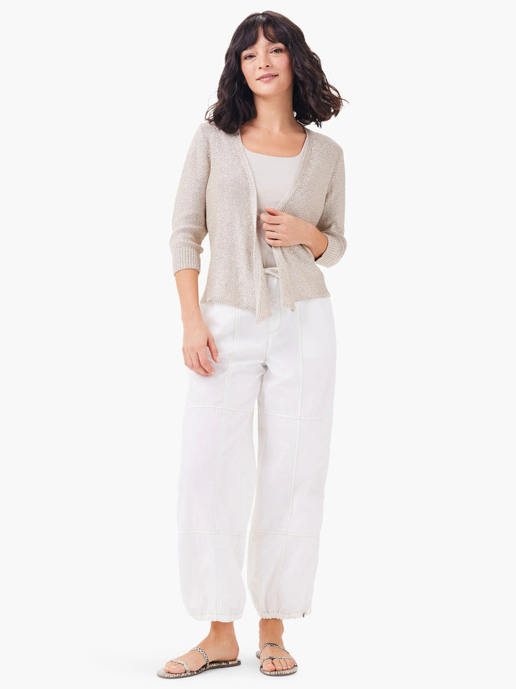 White ankle-length pants with light beige stitching detail. Model is wearing them with a light beige cardigan.