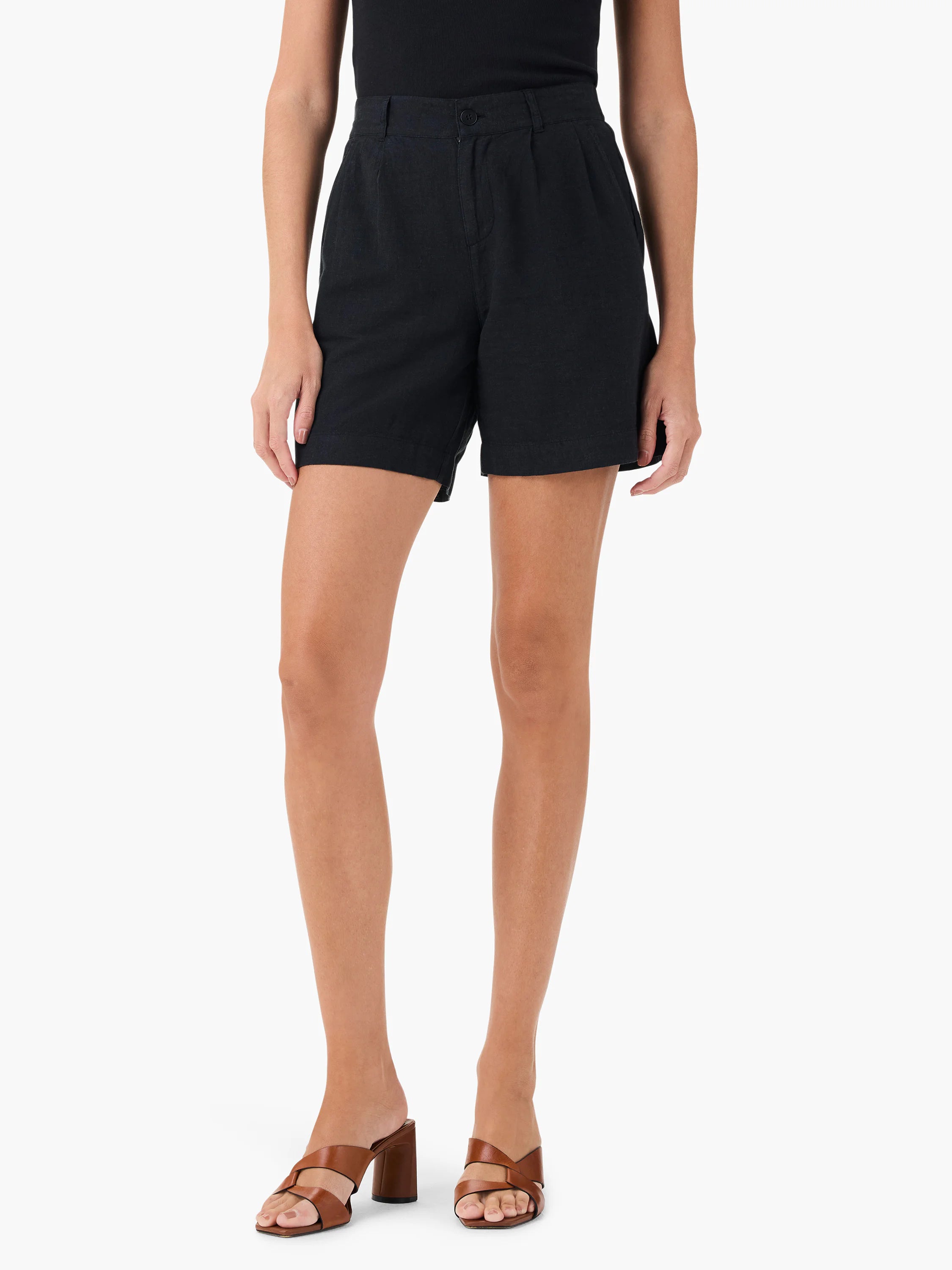 Black linen shorts; pleated waist, mid-thigh length. Model also wearing brown shoes.