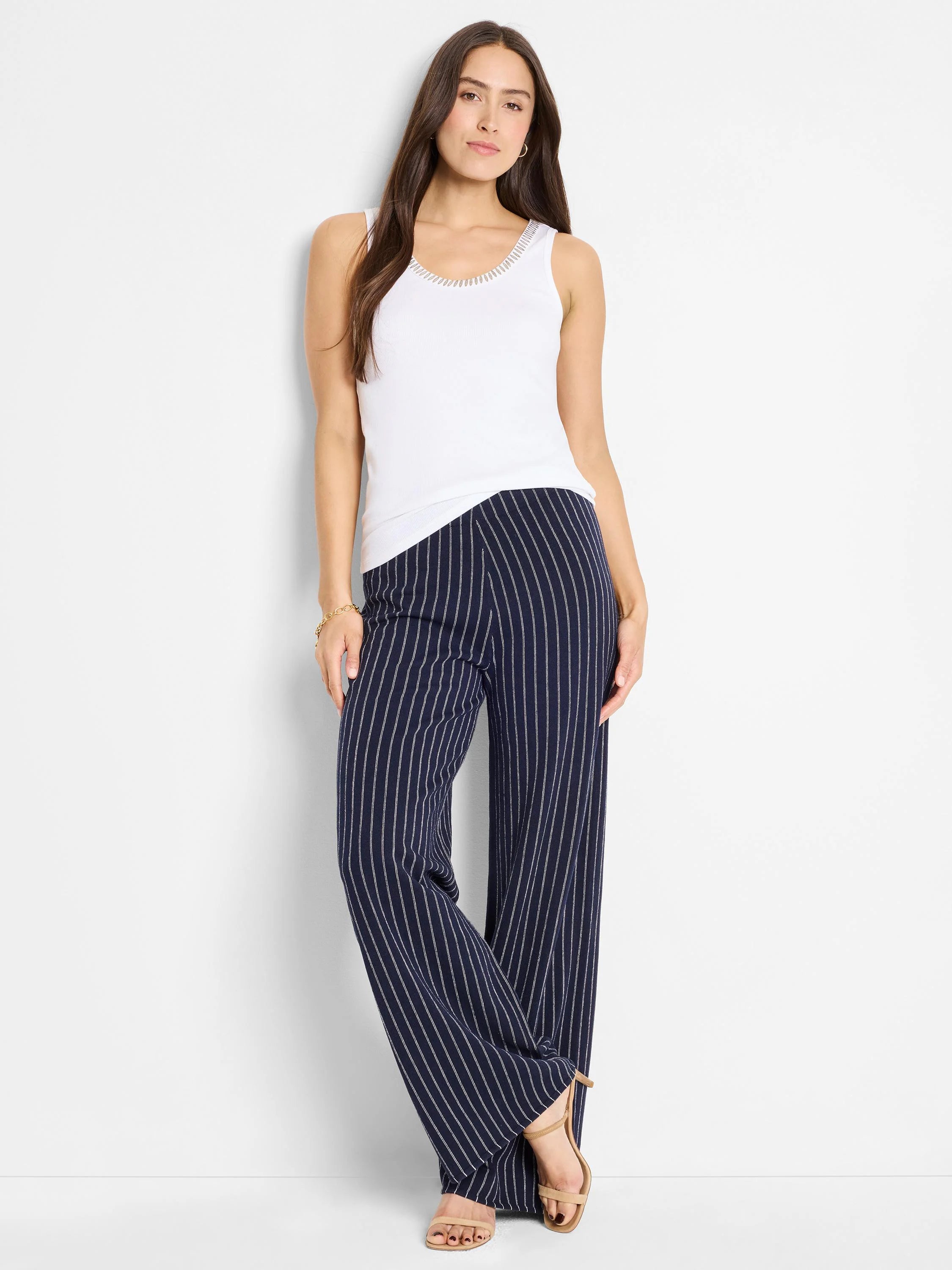 White tank top with light shimmer trim, neckline detail. Paired with navy pinstripe pants.