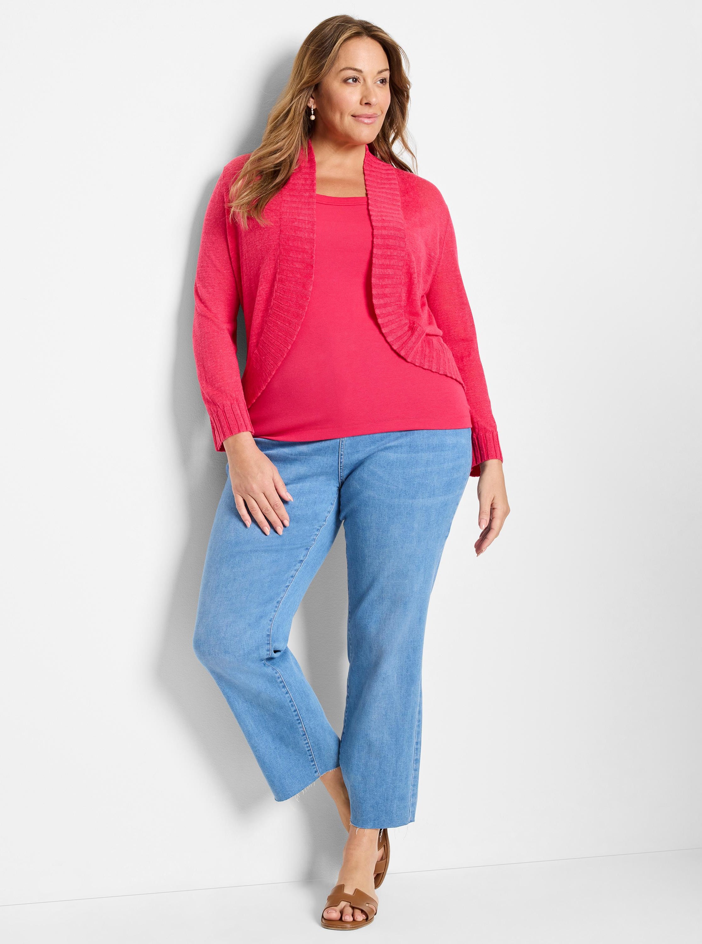 Cropped bright pink knit cardigan featuring a wide ribbed shawl collar, paired with a matching tank and light wash denim.