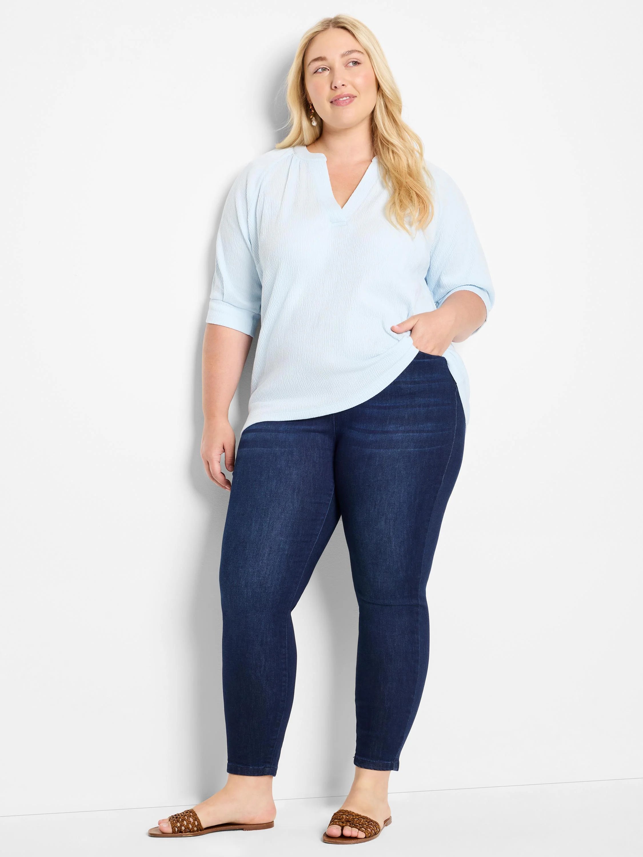 Light blue, textured knit top with a V-neck and three-quarter sleeves. Model is wearing dark wash jeans.