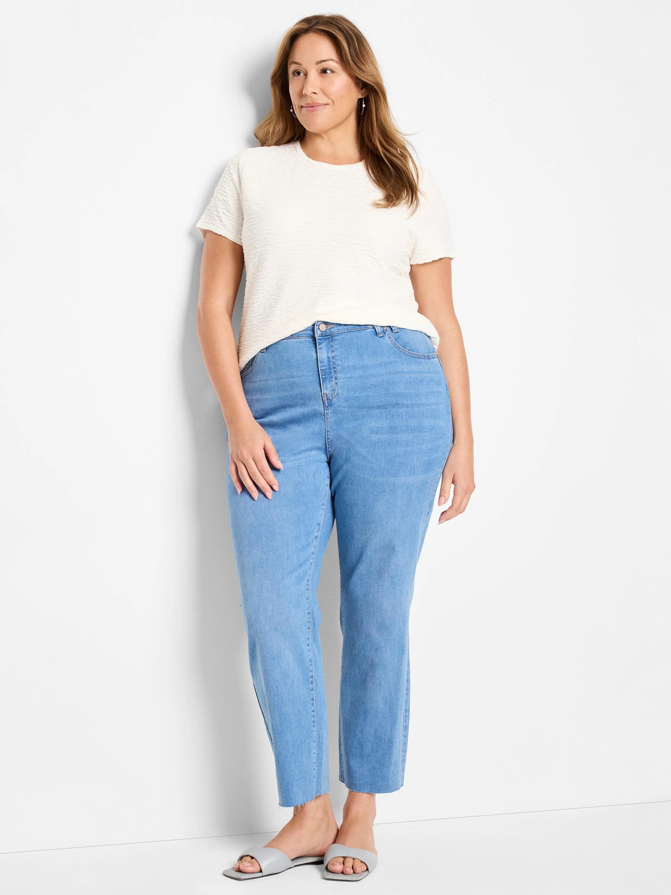 Off-white textured short-sleeved shirt; light blue straight-leg jeans; model is wearing light gray sandals.
