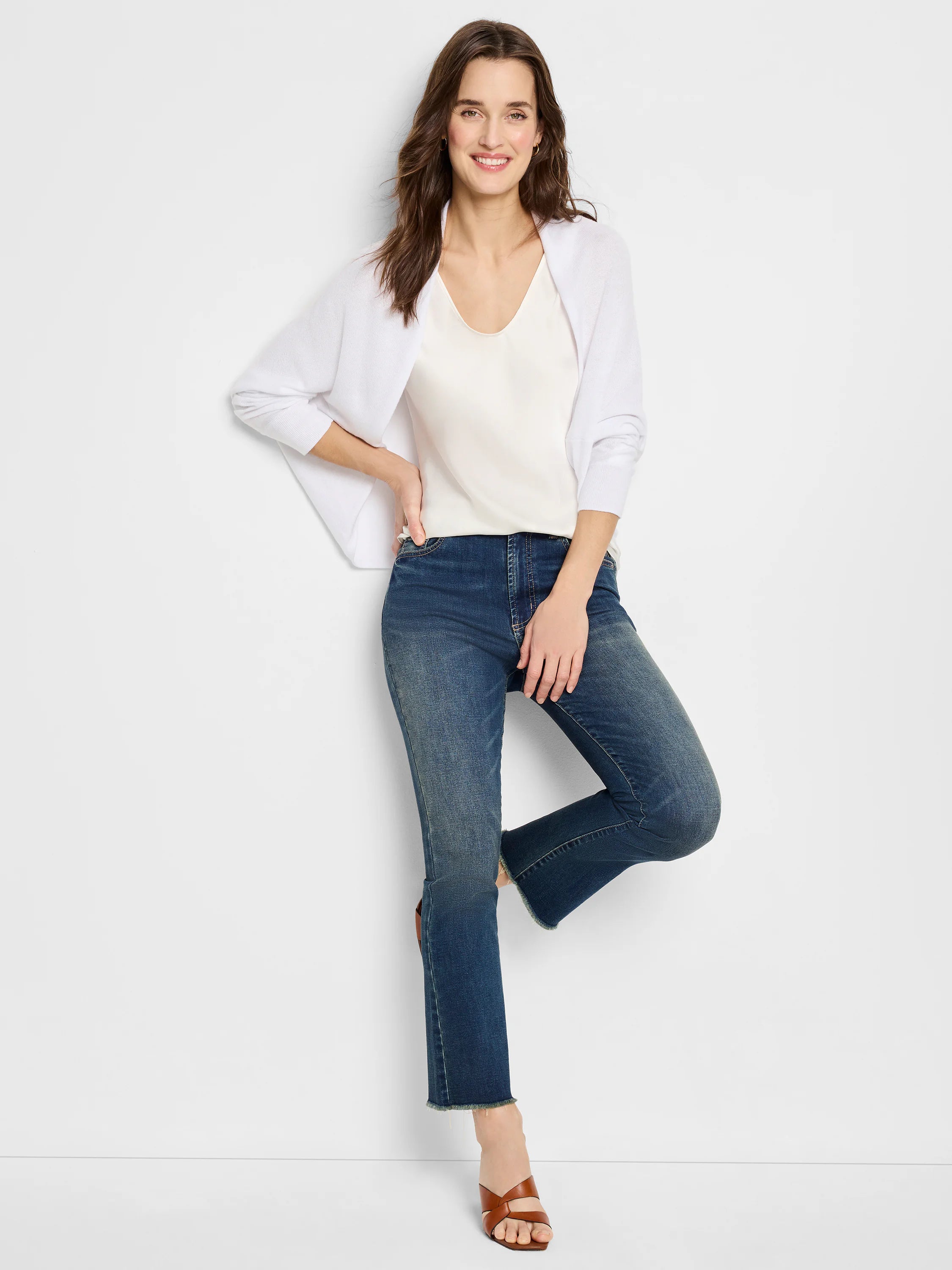 White cotton cashmere shrug cardigan; model shown wearing it over a white top and dark wash jeans.