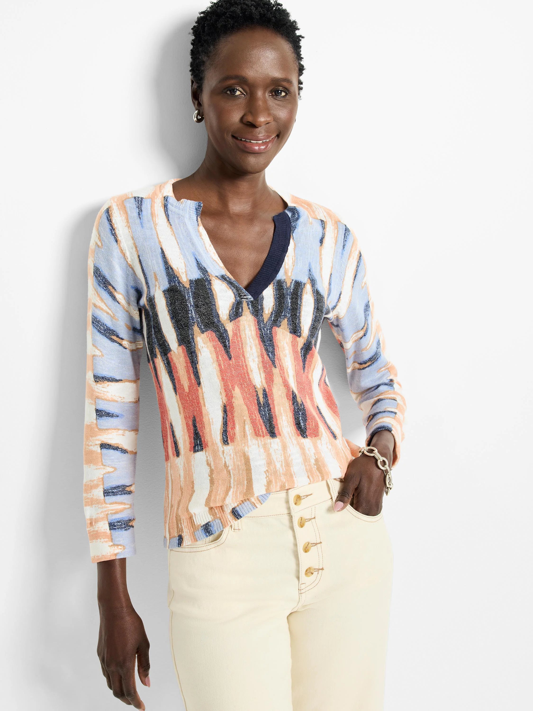 Crisscross V-neck cotton sweater in peach, light blue, and navy abstract print. Long sleeves.