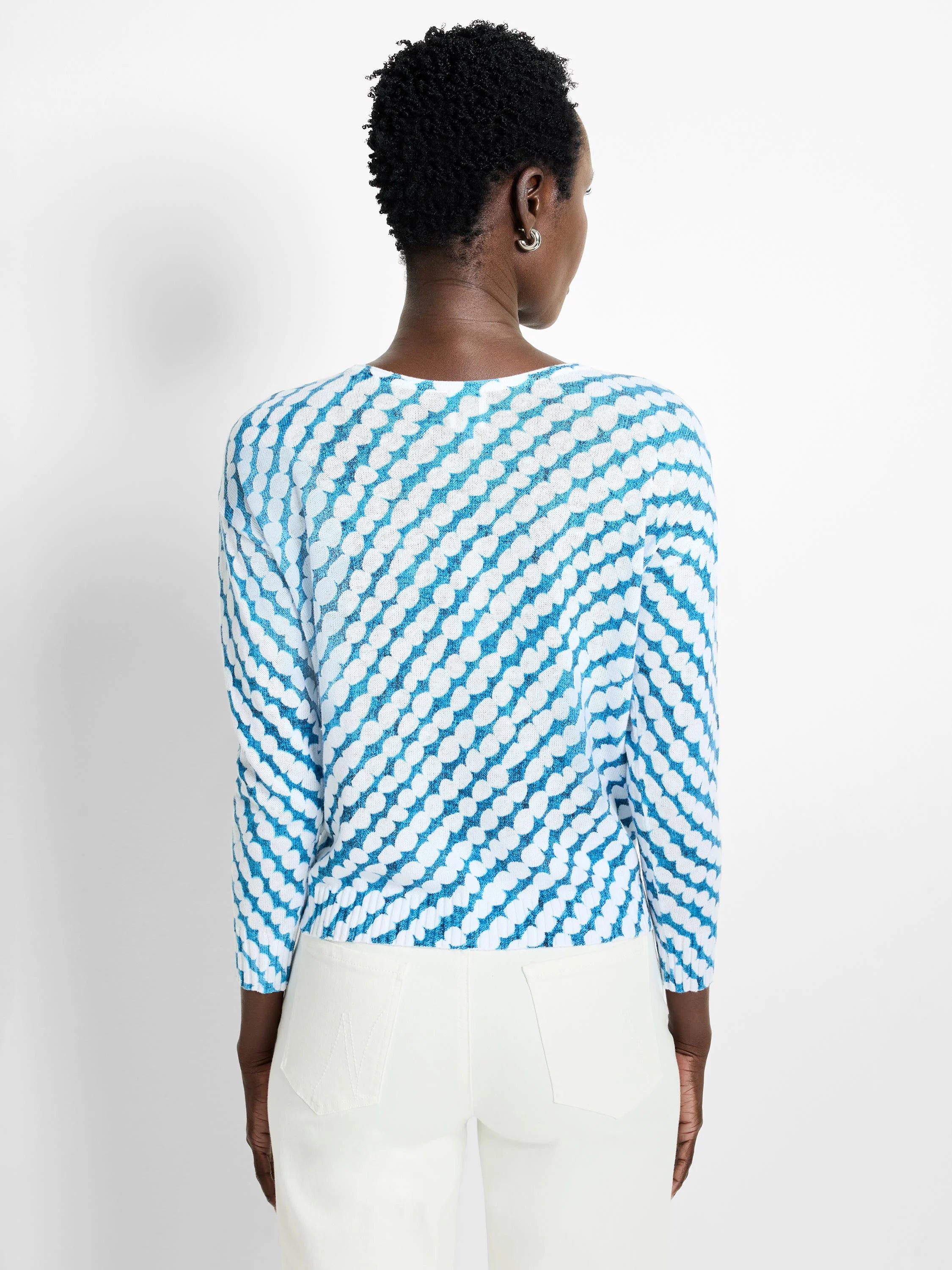 Teal and white patterned sweater; long sleeves, diagonally oriented pattern of small, rounded shapes.