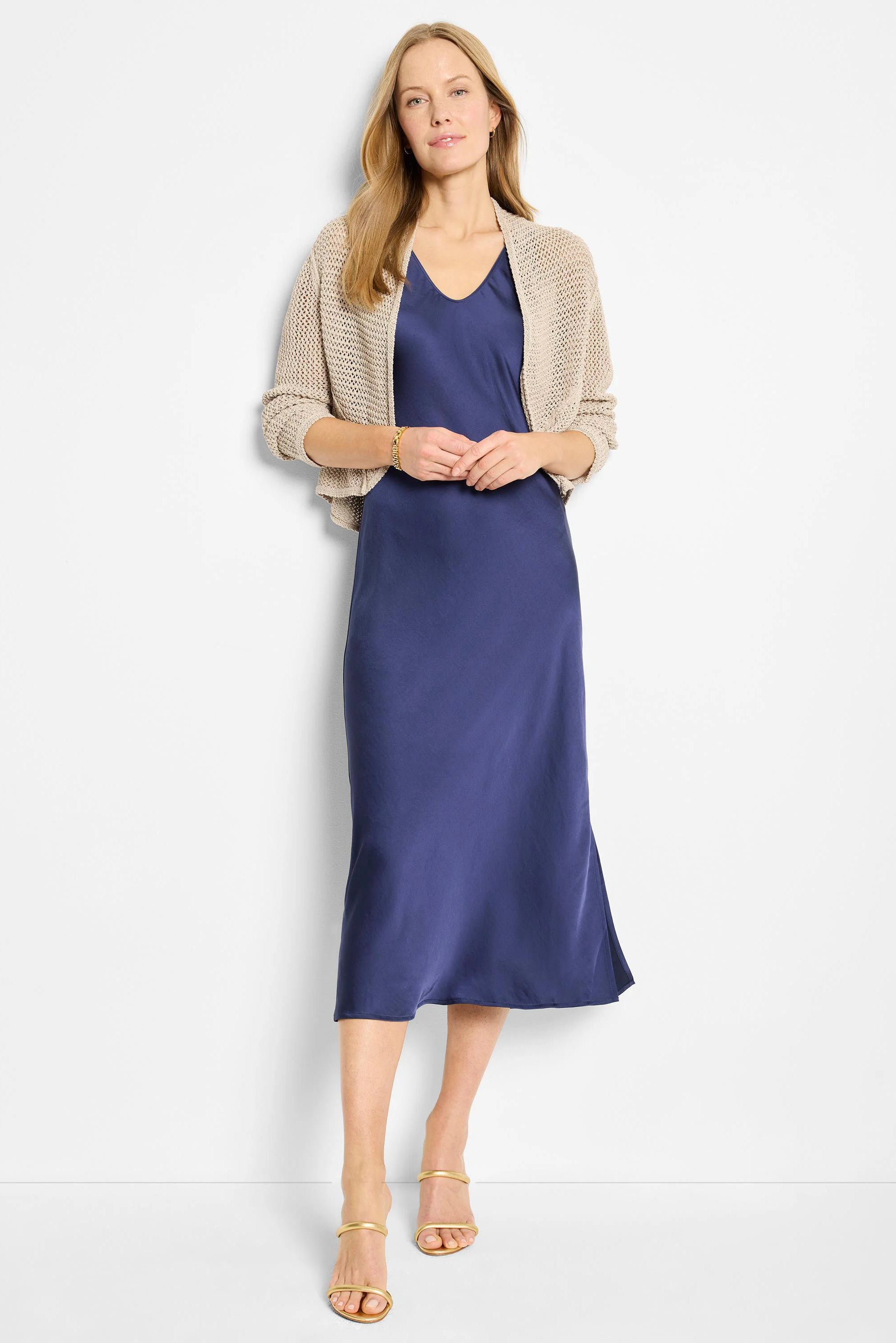 Light beige mesh cocoon cardigan with an open knit, short length, worn over a blue dress.