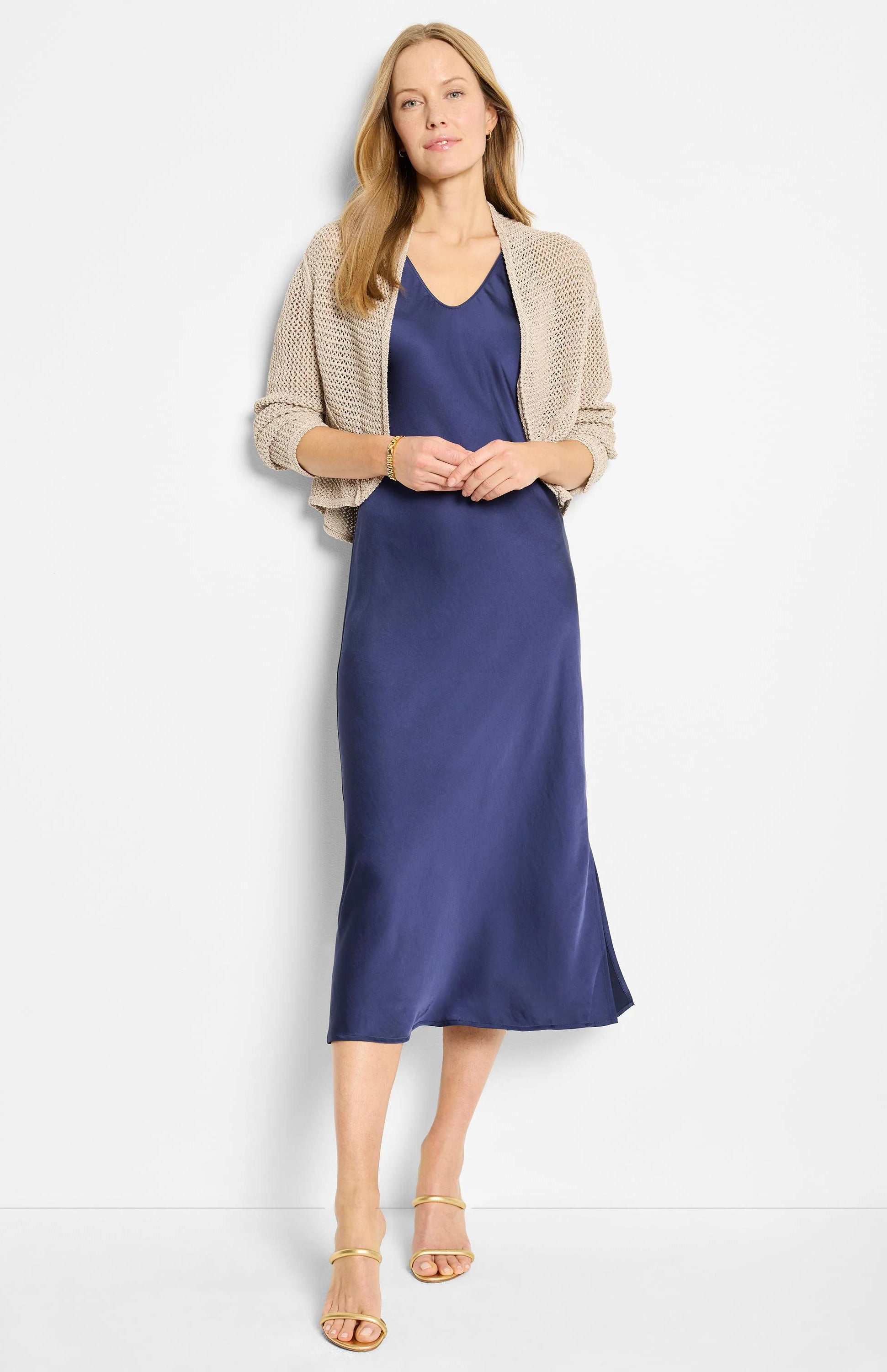 Light beige mesh cocoon cardigan with an open knit, short length, worn over a blue dress.