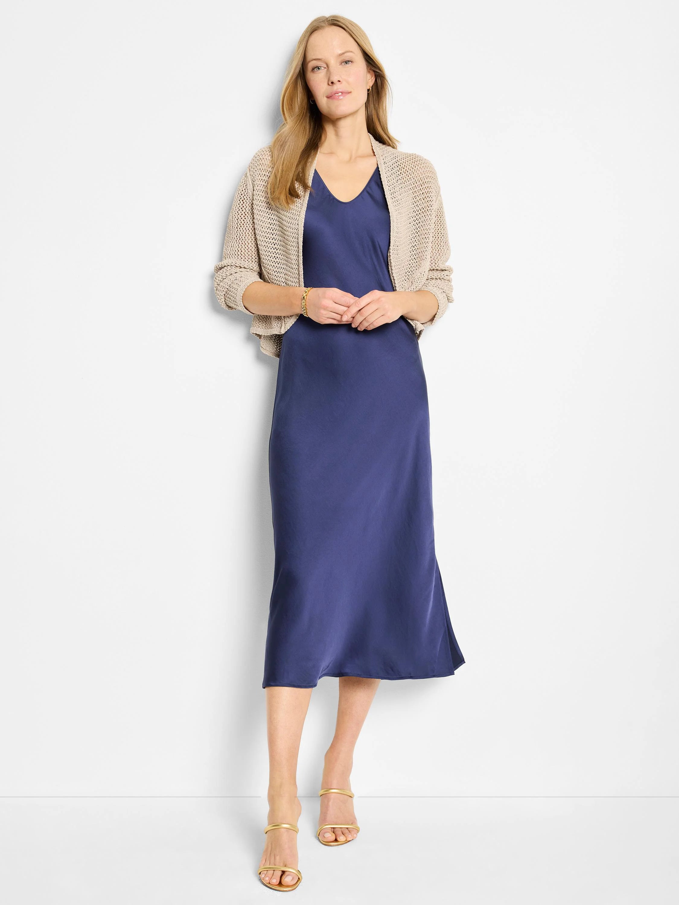 Light beige mesh cocoon cardigan with an open knit, short length, worn over a blue dress.