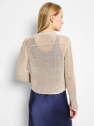 Beige open-knit mesh cocoon cardigan, cropped. Back view on model, showing dark blue underlayer.