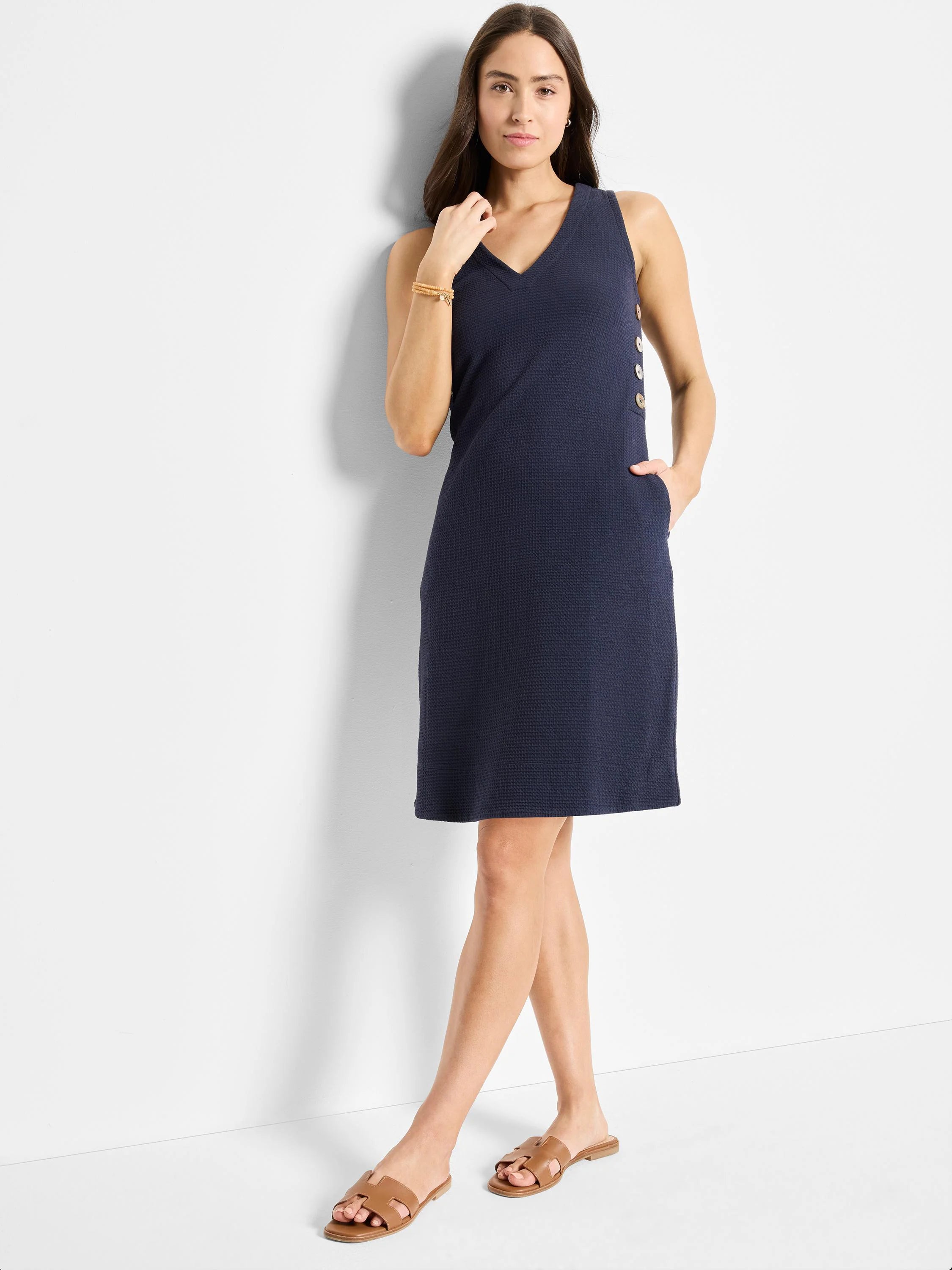 Navy blue, textured sleeveless dress. V-neck, side buttons, and pockets.