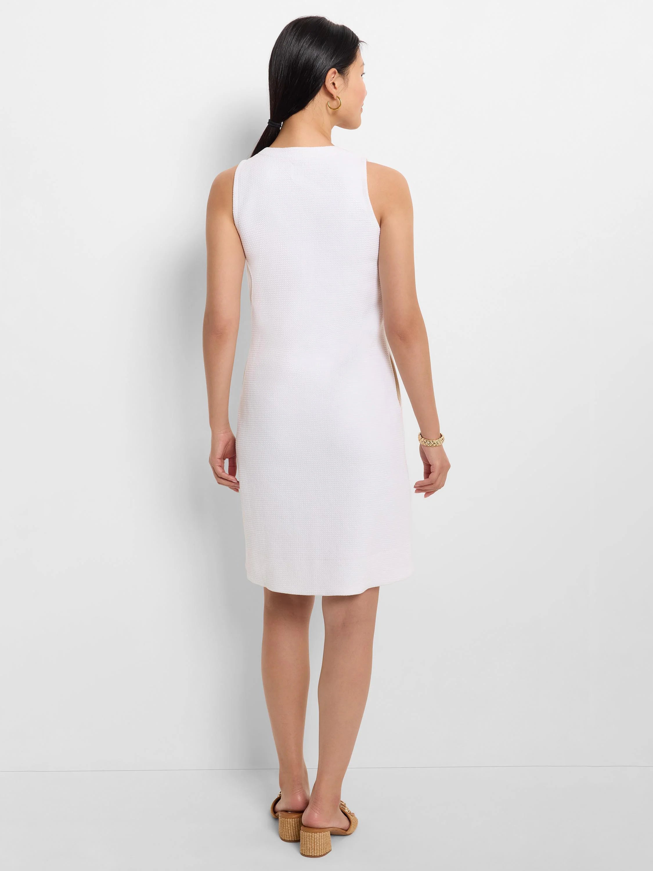 White, sleeveless, textured cotton dress; A-line silhouette, above-knee length.