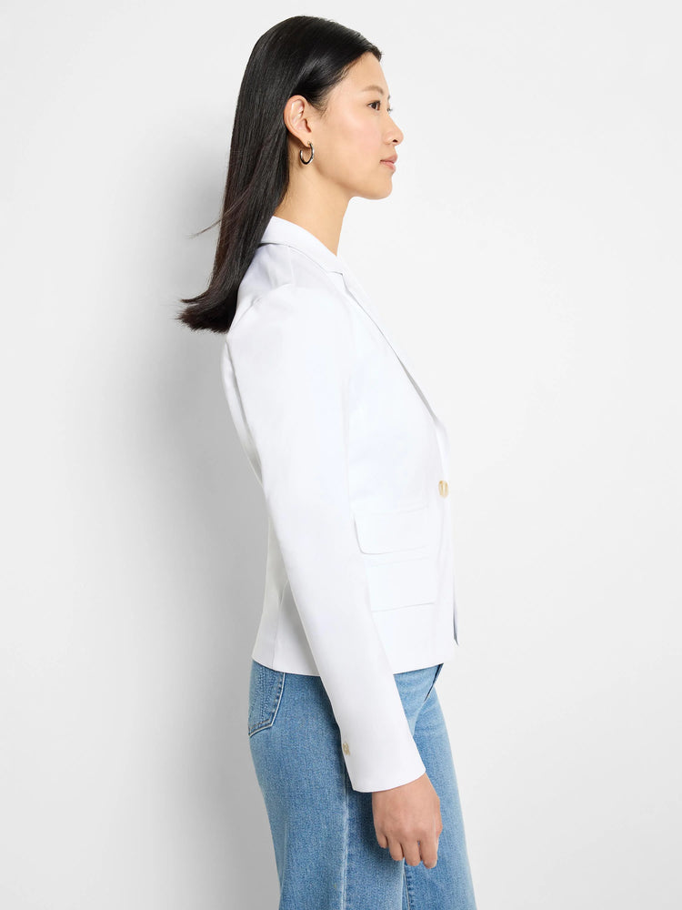 White blazer, side view. Features two pockets and gold buttons. The blazer has long sleeves with buttoned cuffs.