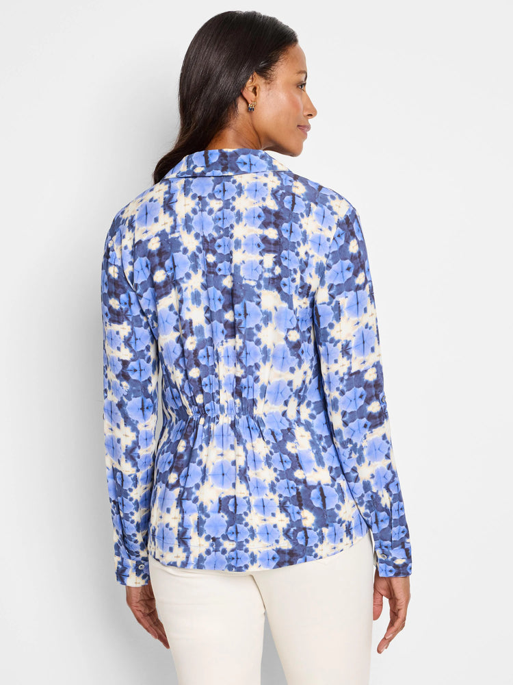 Shibori stone shirt, back view. Blue, beige, and dark-blue tie-dye pattern. Long sleeves, button cuffs, and fitted waist.
