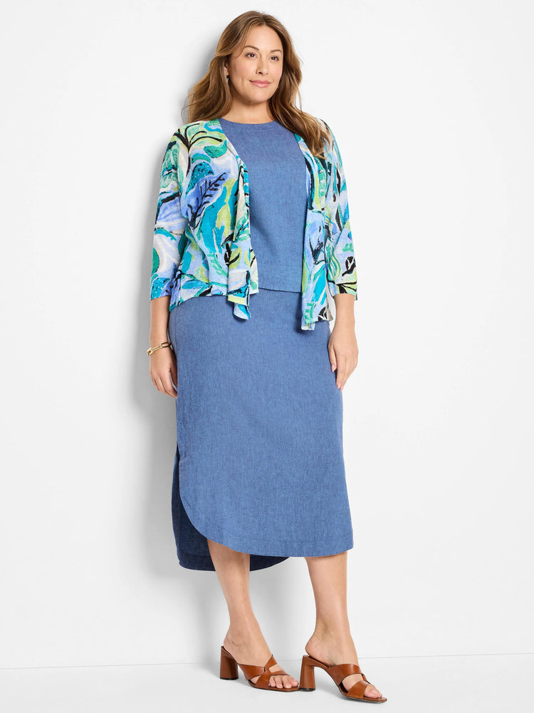 Blue linen midi skirt, asymmetrical hem, side slits. Model also wears teal/green floral cardigan.