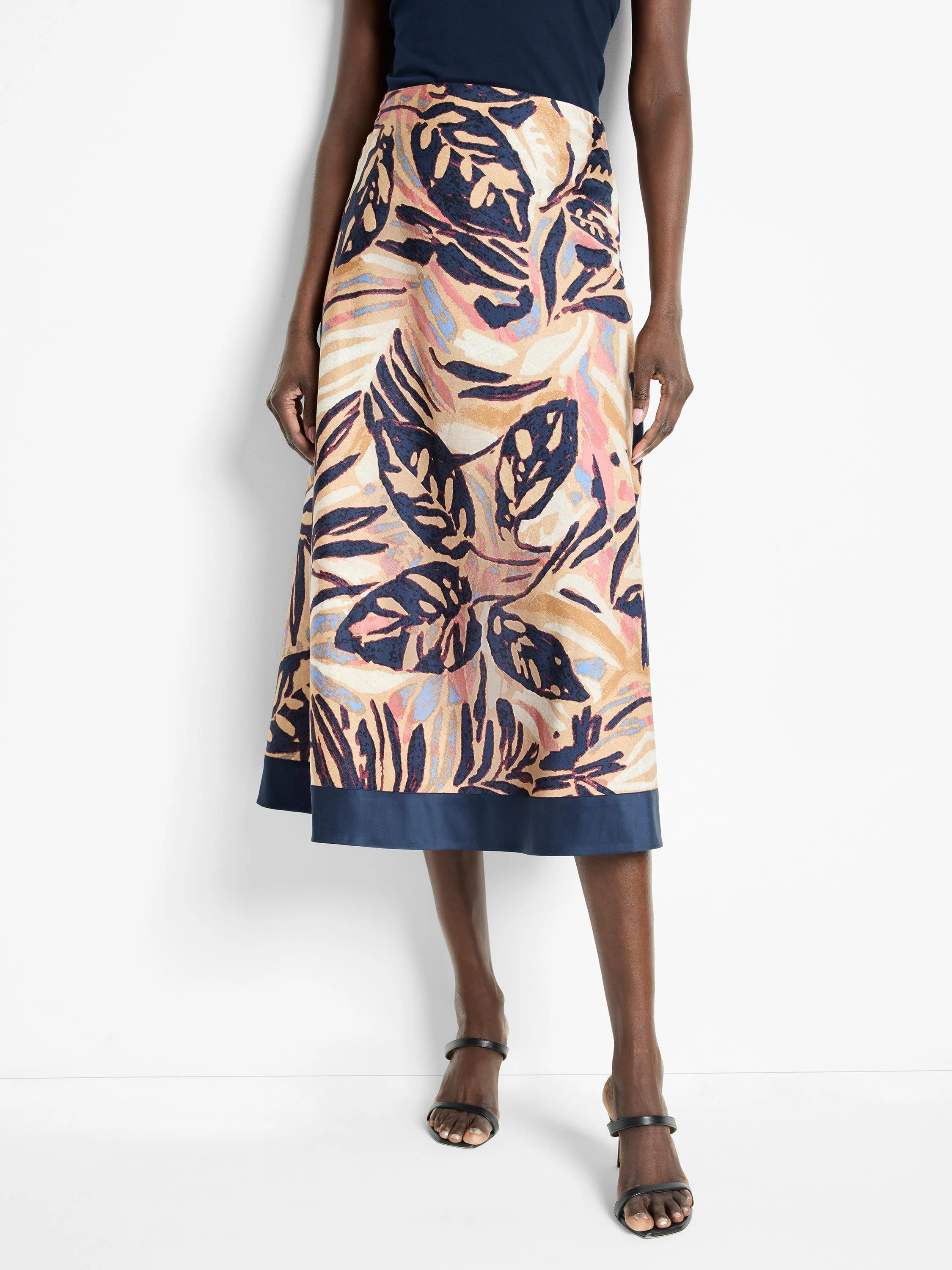 Midi-length terracotta skirt with a dark navy blue bottom band. Features a leaf print in shades of beige, dark blue, and...