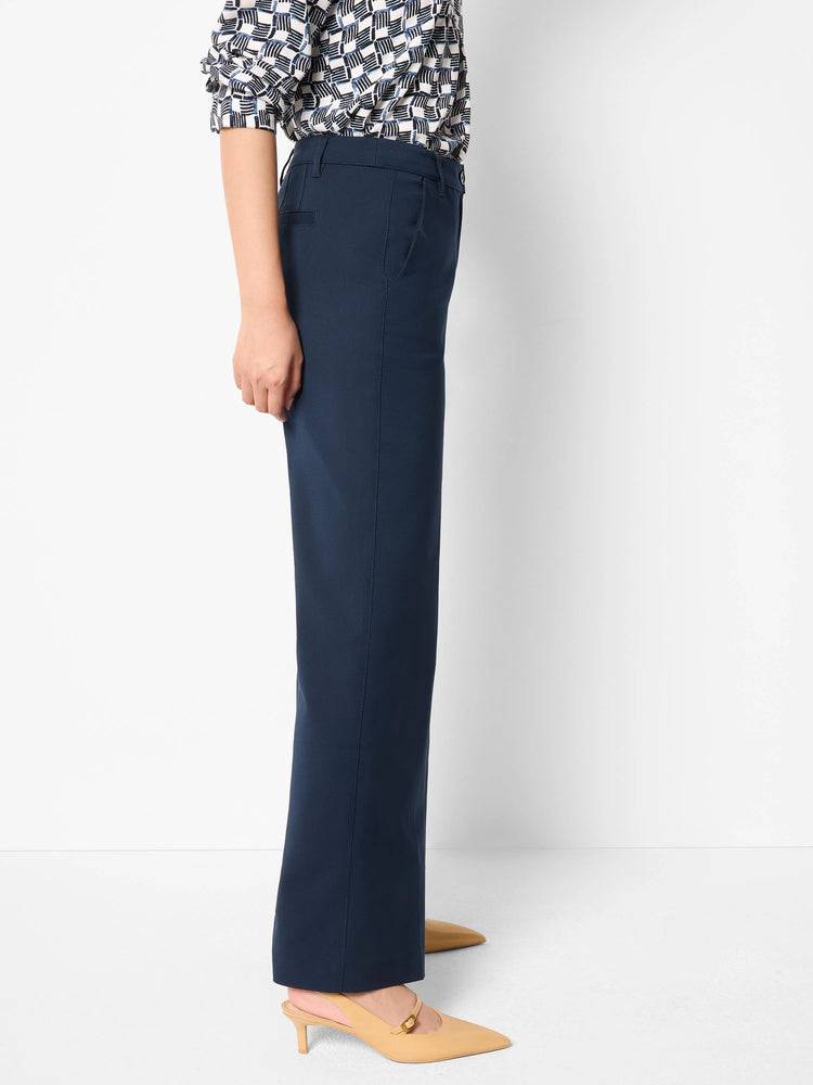 Image of navy blue wide-leg trousers on a model. The pants have a straight leg and are shown from the side.