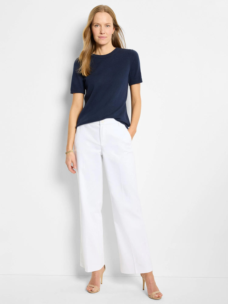 White wide-leg cotton trousers on a model. The trousers are shown with a dark navy top and nude heels.