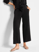 Black wide-leg linen pants with a black rope belt featuring tassels.