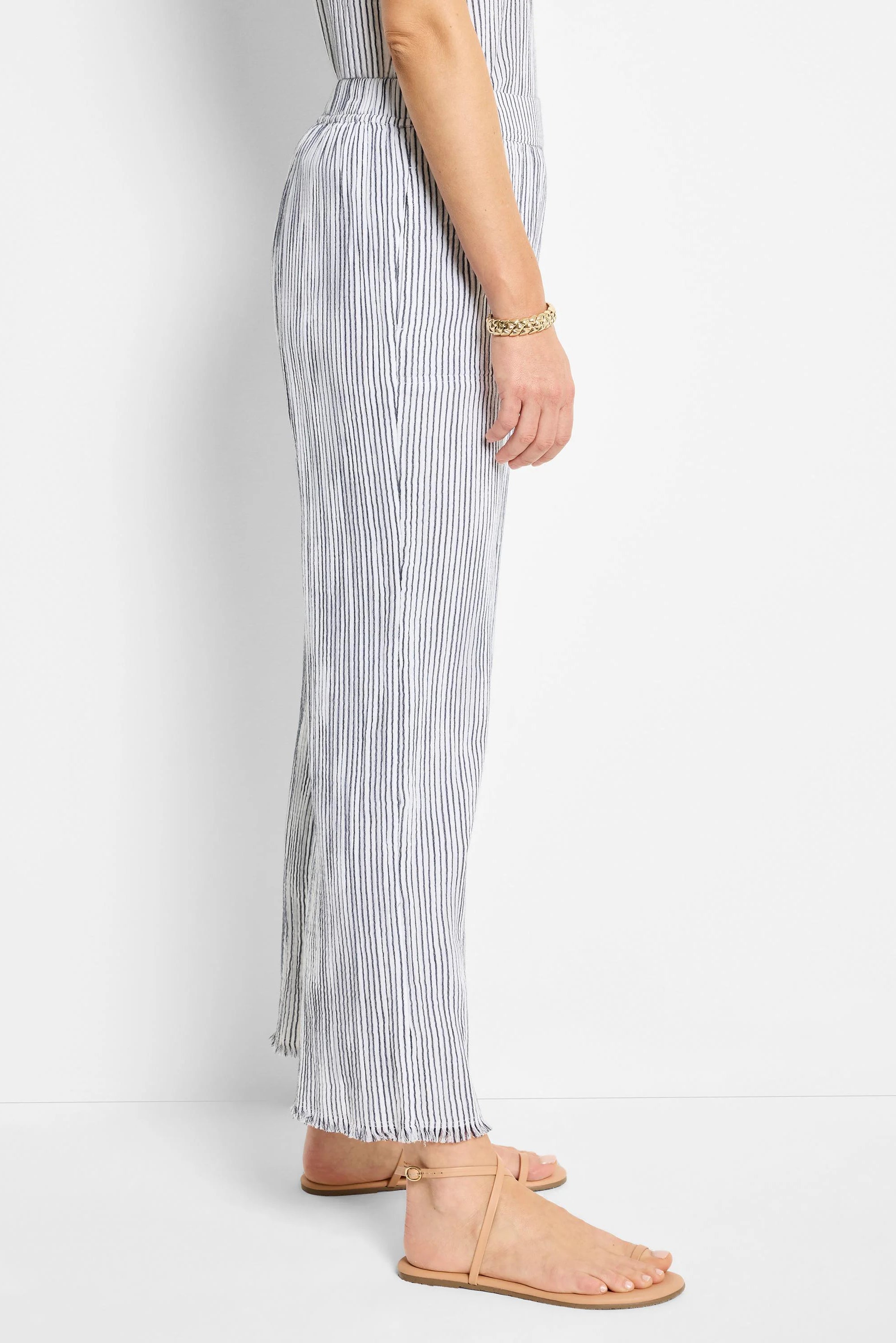 White wide-leg pants with thin, dark blue pinstripes; raw hem.