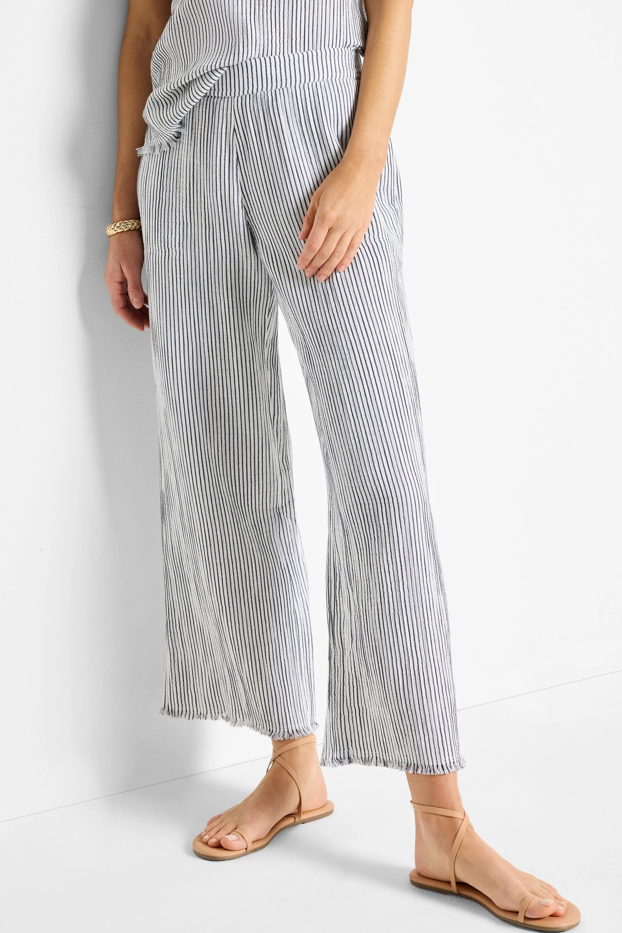 White wide-leg pants with thin navy pinstripes, raw hem.