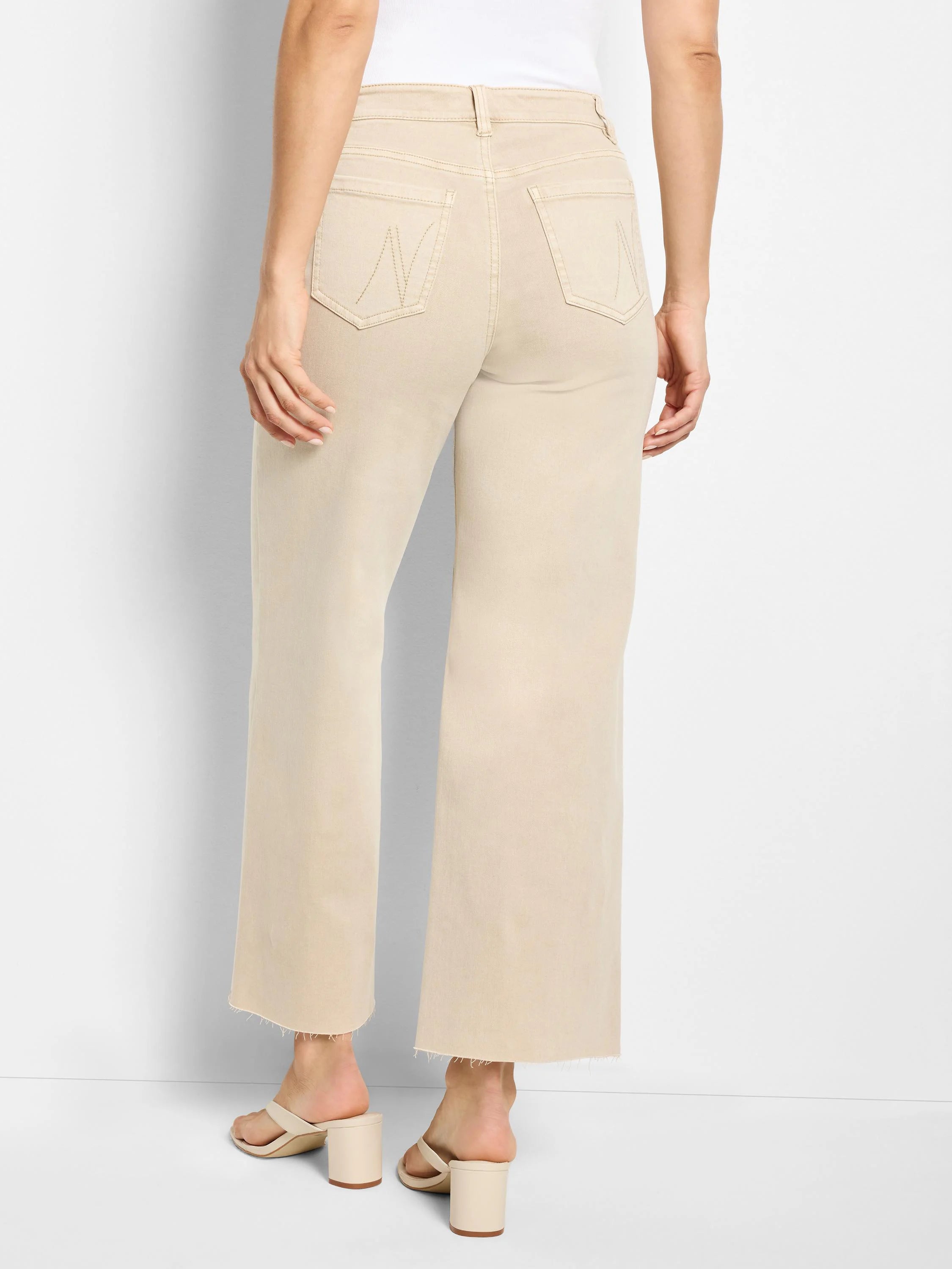 Back view of light beige wide leg jeans with high waist, back pockets, and frayed raw hems.