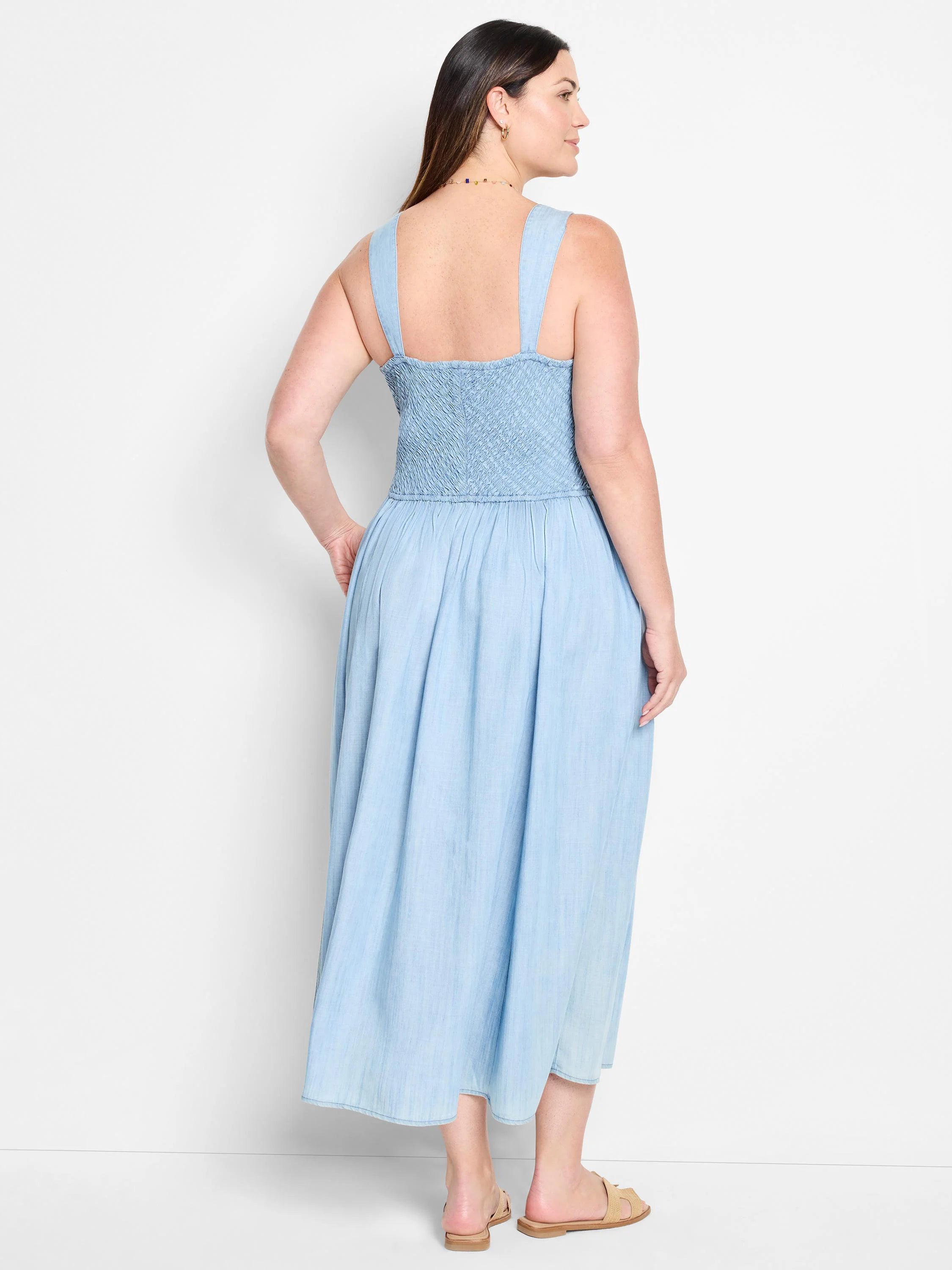 Light blue denim midi dress with smocked bodice and thin straps.  Back view.