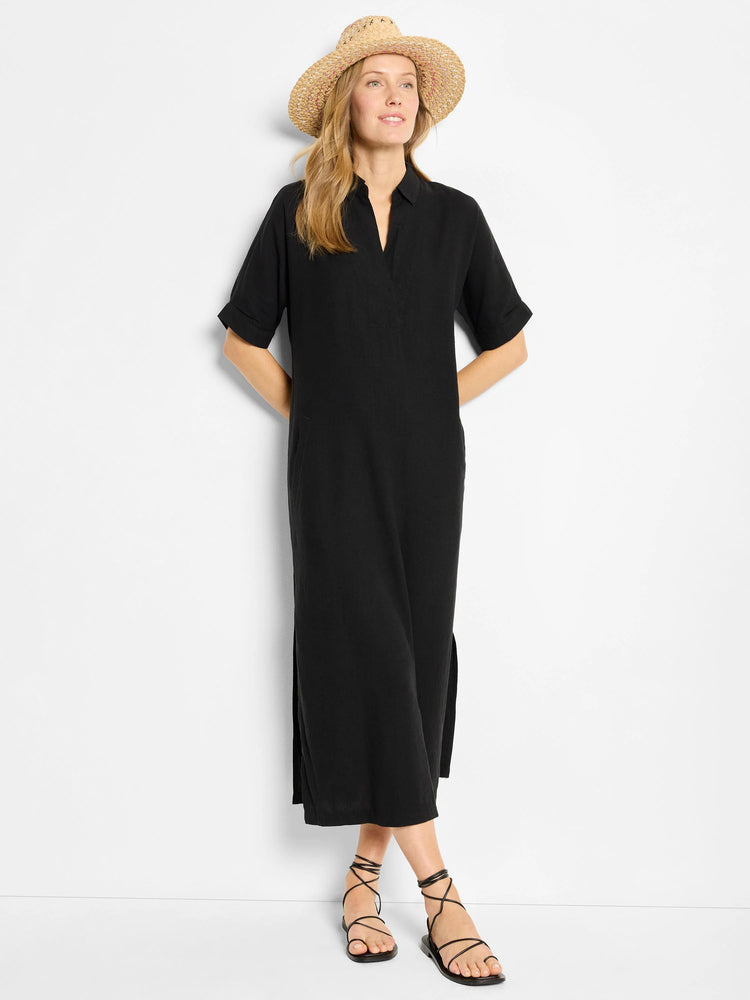 Black linen tunic dress, short sleeves, knee-length, side slits. Model wears it with sandals and hat (not included).