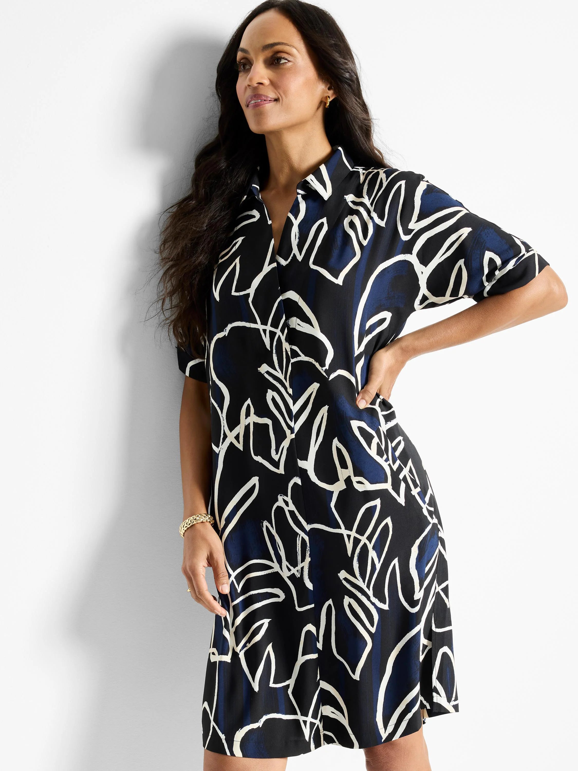 Black shirt dress with navy and off-white abstract leaf print. Short sleeves, collared neckline.