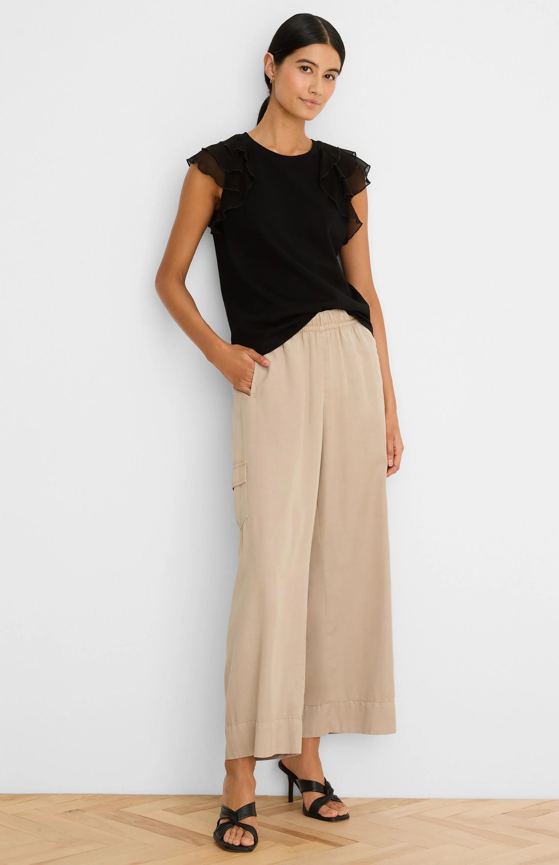 Black top with sheer ruffled chiffon cap sleeves and a round neckline.
