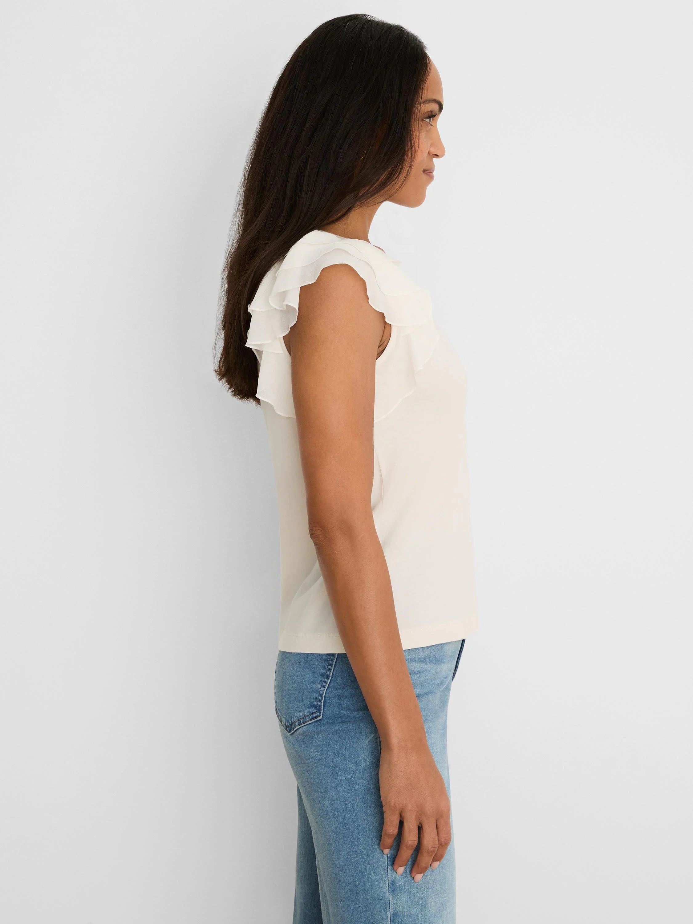 Cream chiffon top with layered ruffle short sleeves, worn by a model in profile.