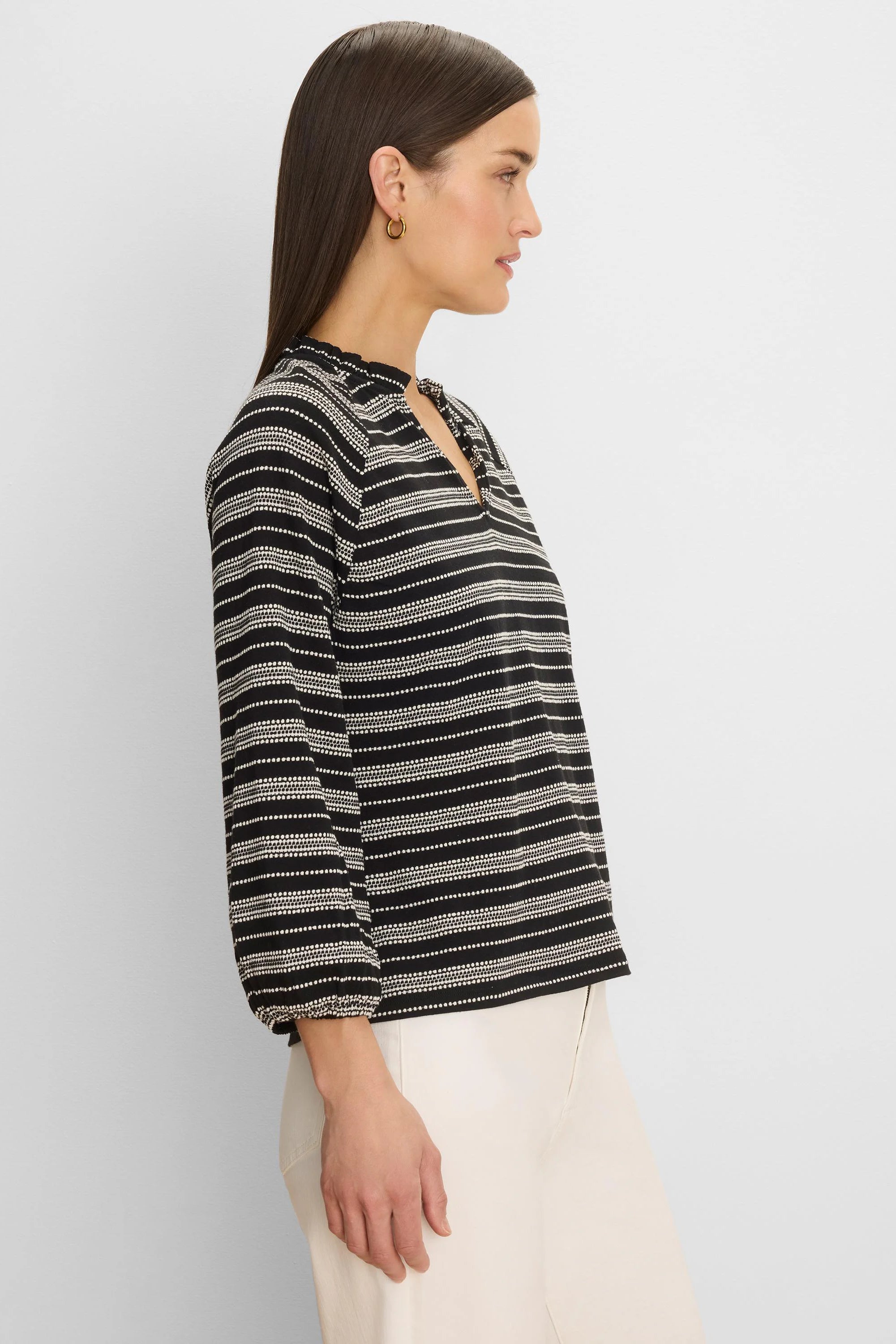 Black & white knit top with dotted horizontal stripes, ruffled high neck, V-slit, and long sleeves.